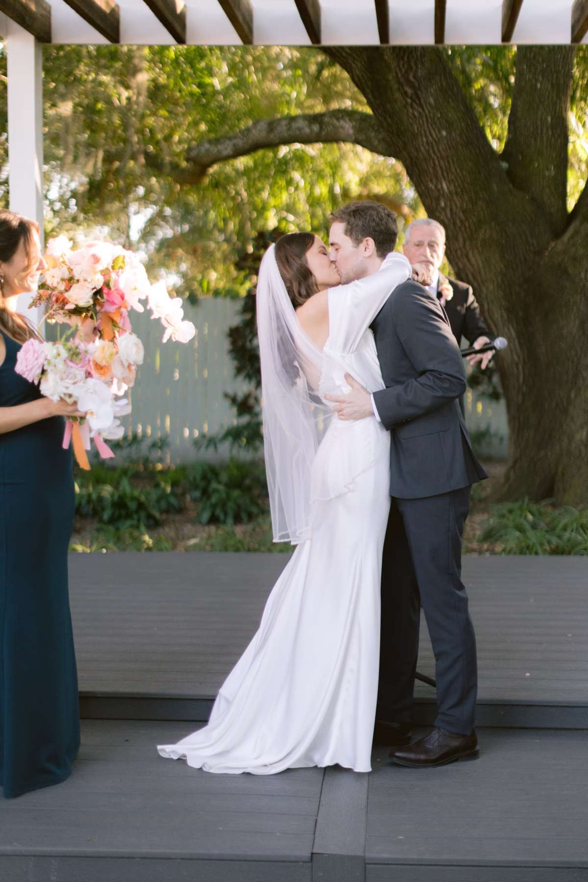 Bride and groom share their first kiss during outdoor wedding ceremony at Soire Estate in Tampa with Golden Wild Florals arrangements