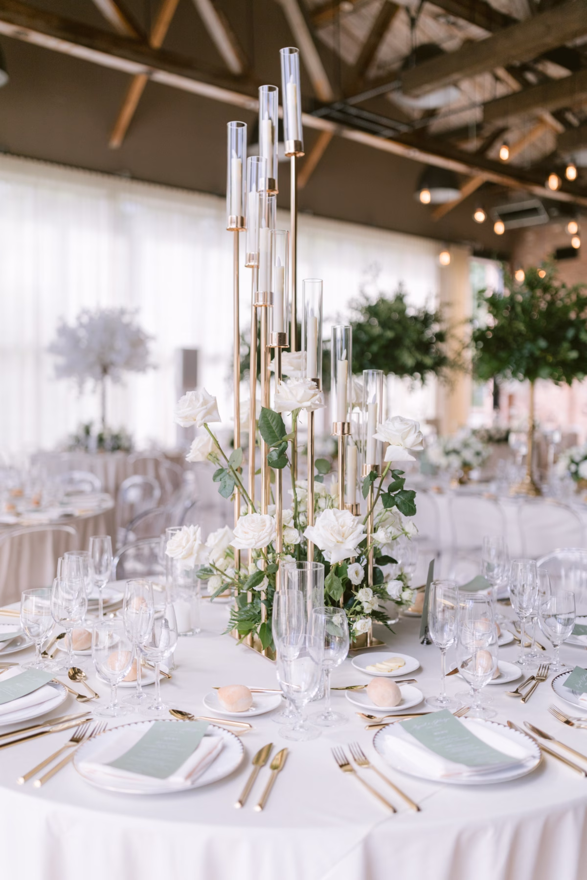 Elegant tall gold candelabra centerpiece with white roses by Maky The Diva Flowers at The Roundhouse Beacon wedding venue in Hudson Valley