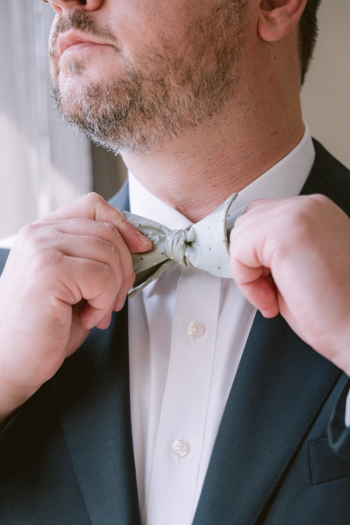 Groom adjusting his bowtie while getting ready for his art museum wedding in St. Petersburg captured by Ashley Izquierdo Photography