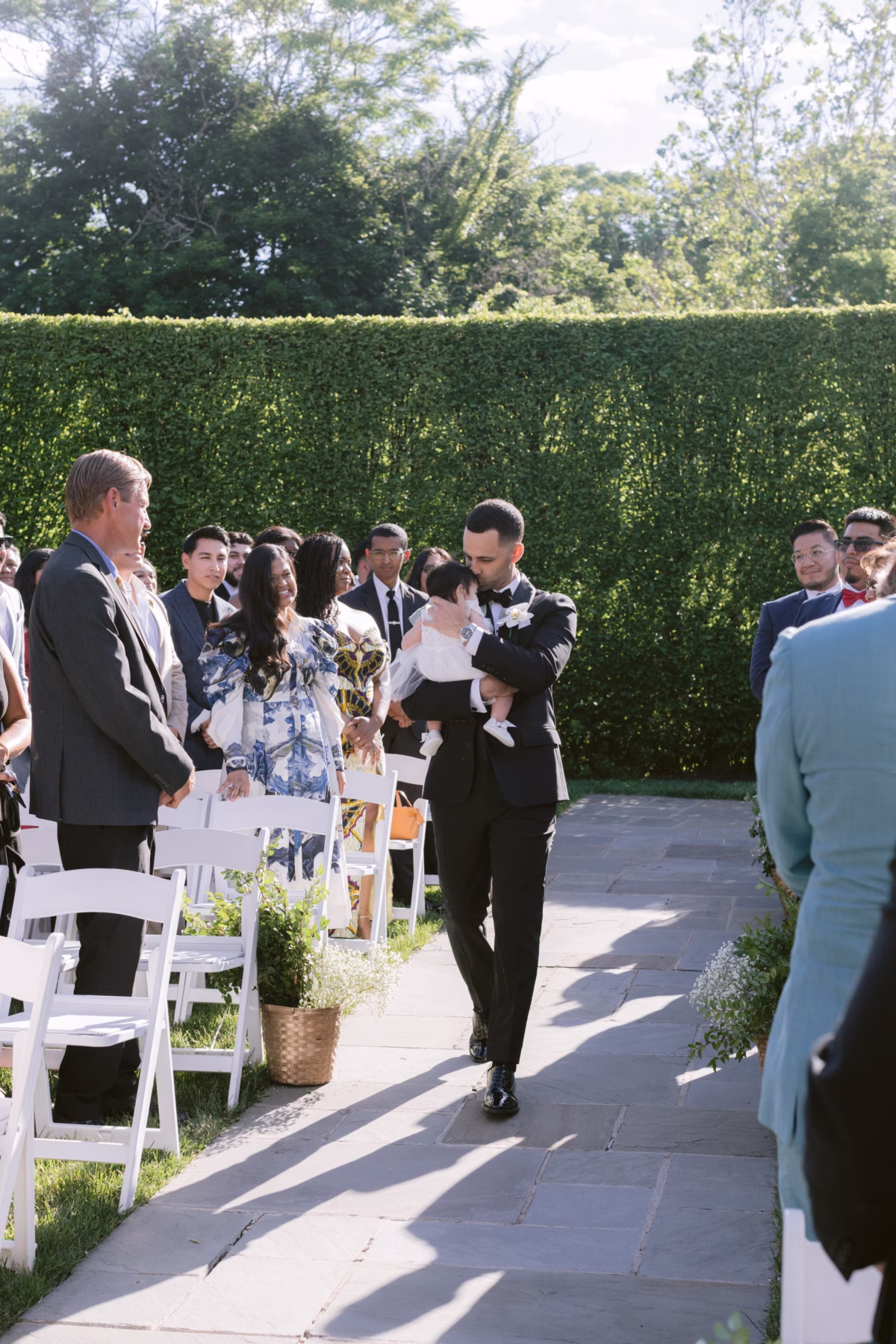 Groom carrying baby during outdoor wedding ceremony at The Roundhouse Beacon venue in Hudson Valley