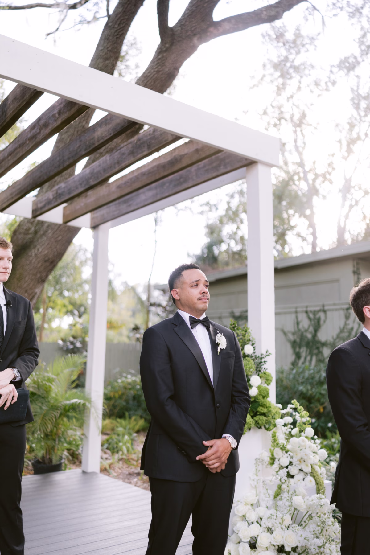 Groom waiting at outdoor wedding ceremony at Soire Estate Tampa with white floral arrangements by Ava Elise Decor