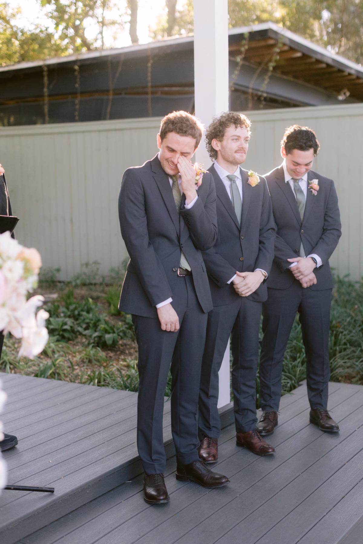 Emotional groom wiping tears during wedding ceremony with groomsmen at Soire Estate Tampa, wearing Suit Shop attire