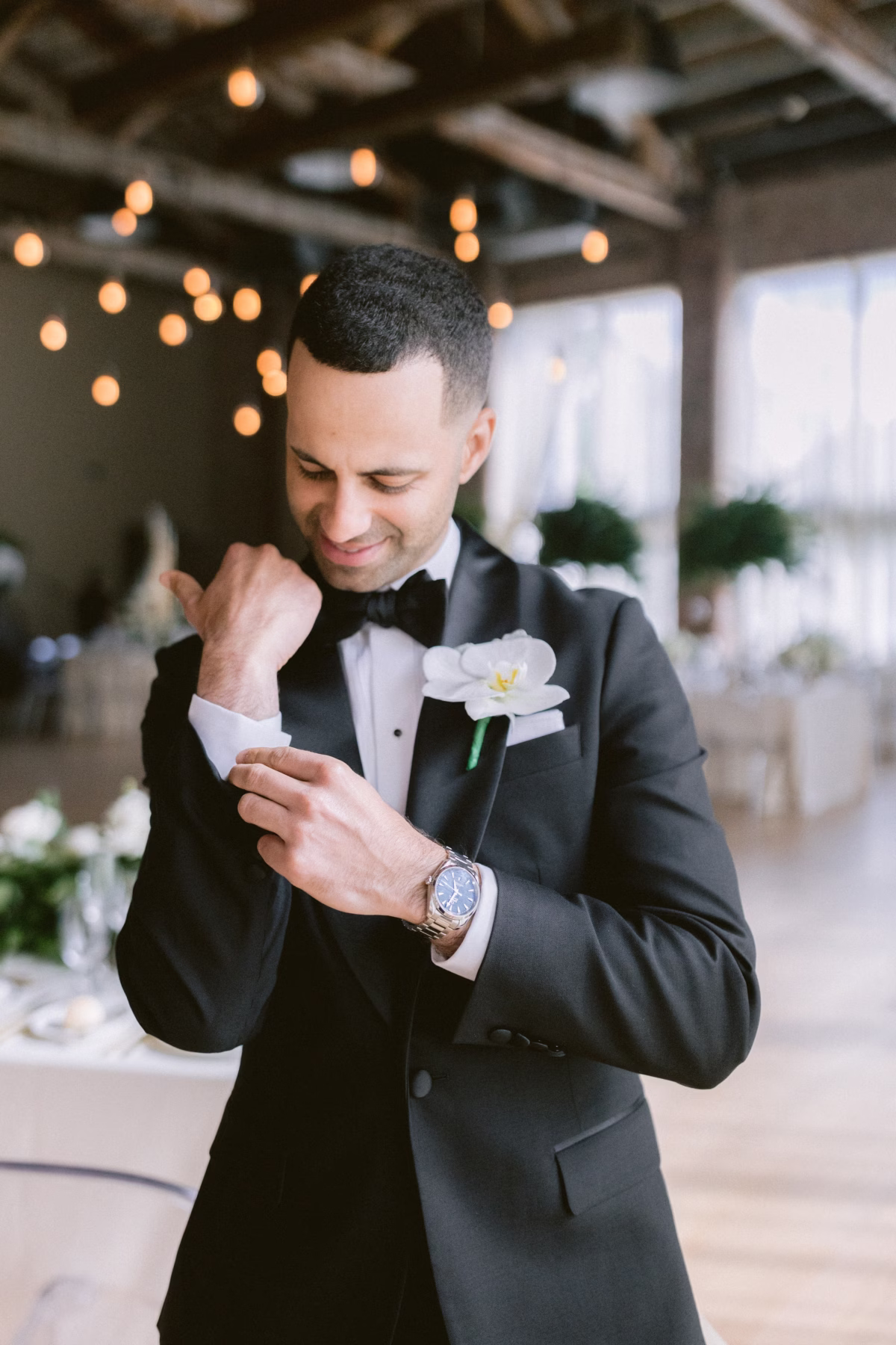 Groom adjusting cufflinks with white boutonniere by Maky The Diva Flowers at The Roundhouse Beacon Hudson Valley wedding