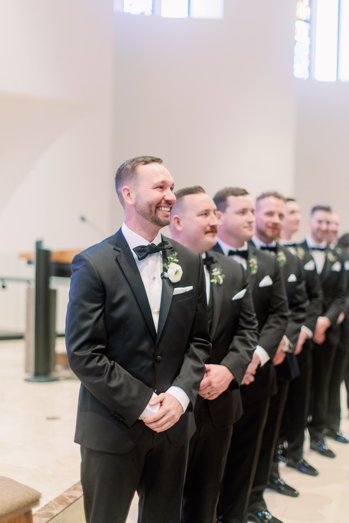 Groom and groomsmen in black tuxedos watching bride's entrance during waterfront wedding ceremony at The Vinoy St. Petersburg planned by Lemon Drops Weddings and Events