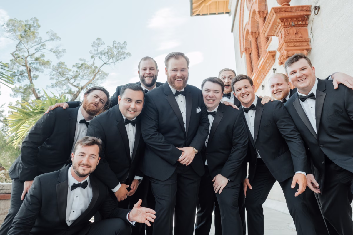 Groomsmen in black tuxedos pose for group photo at historic Lightner Museum wedding in St. Augustine