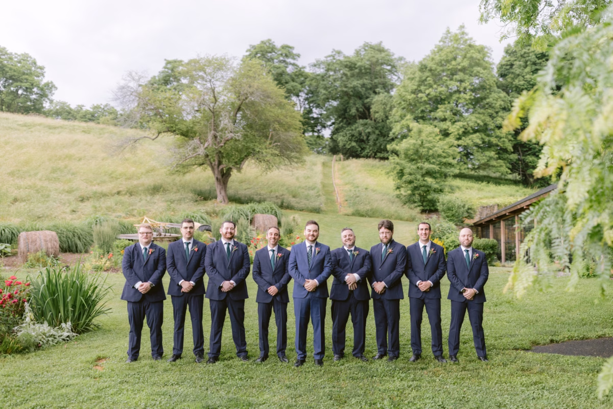 Nine groomsmen in navy suits pose for formal portraits at Red Maple Vineyard captured by Ashley Izquierdo Photography