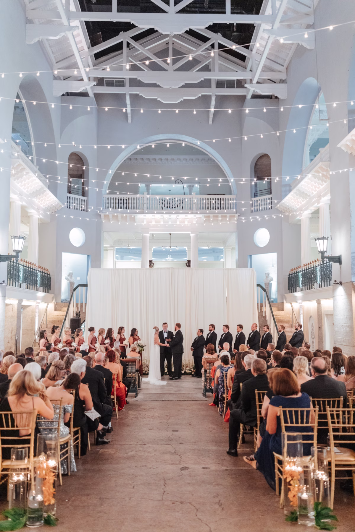 Historic wedding ceremony at The Lightner Museum with string lights and elegant decor by Coastal Celebrations wedding planning