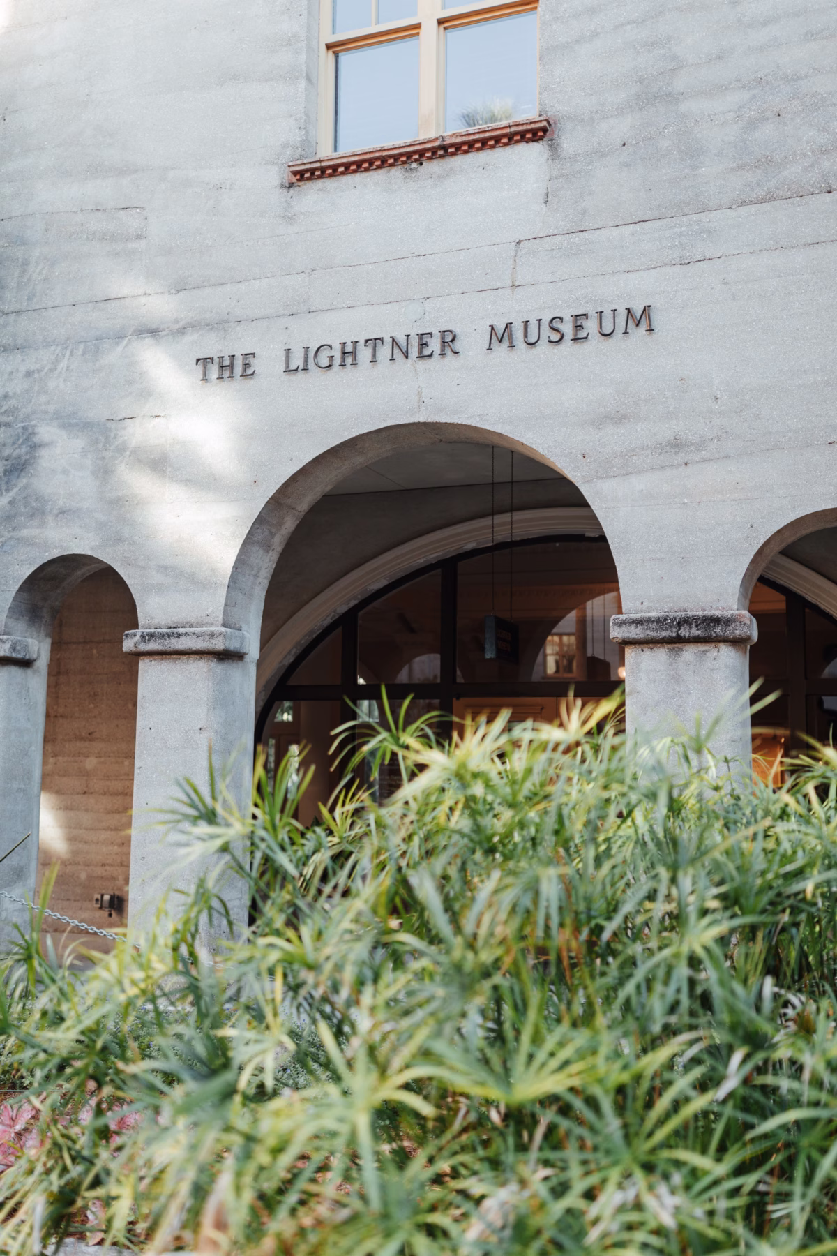 Historic wedding venue entrance at The Lightner Museum in St Augustine featuring stone arches and lush landscaping photographed by Ashley Izquierdo Photography