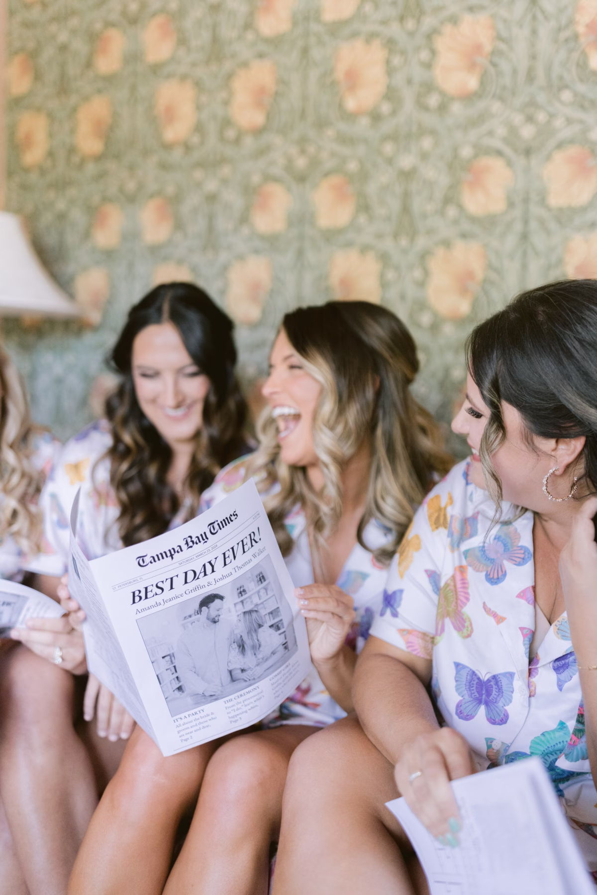 Bridesmaids in floral robes reading Tampa Bay Times newspaper during getting ready at Hostess House with Day of Details wedding planning coordination in St. Pete