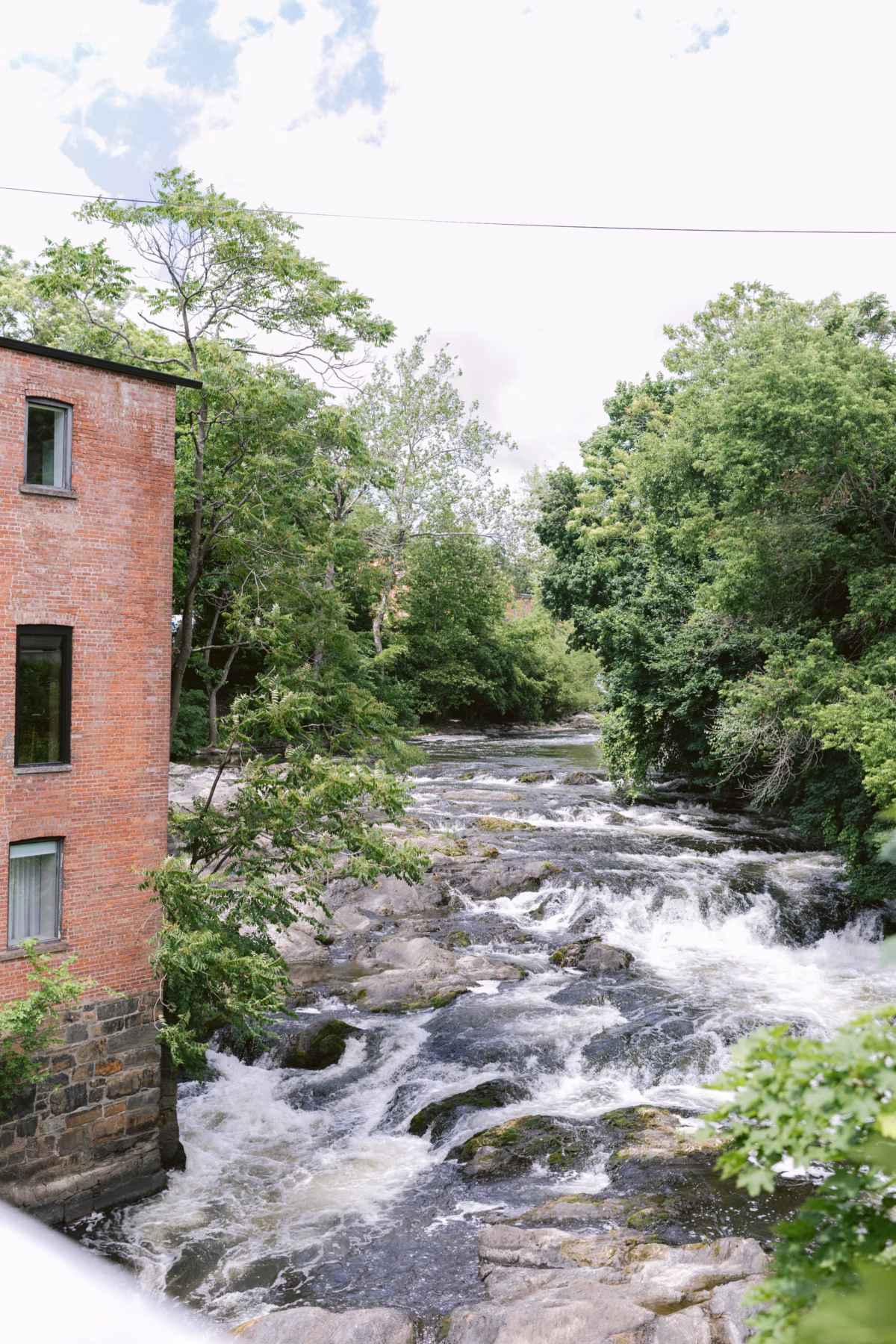 Rushing waterfall rapids flow past historic brick building at The Roundhouse Beacon wedding venue in Hudson Valley New York photographed by Ashley Izquierdo Photography