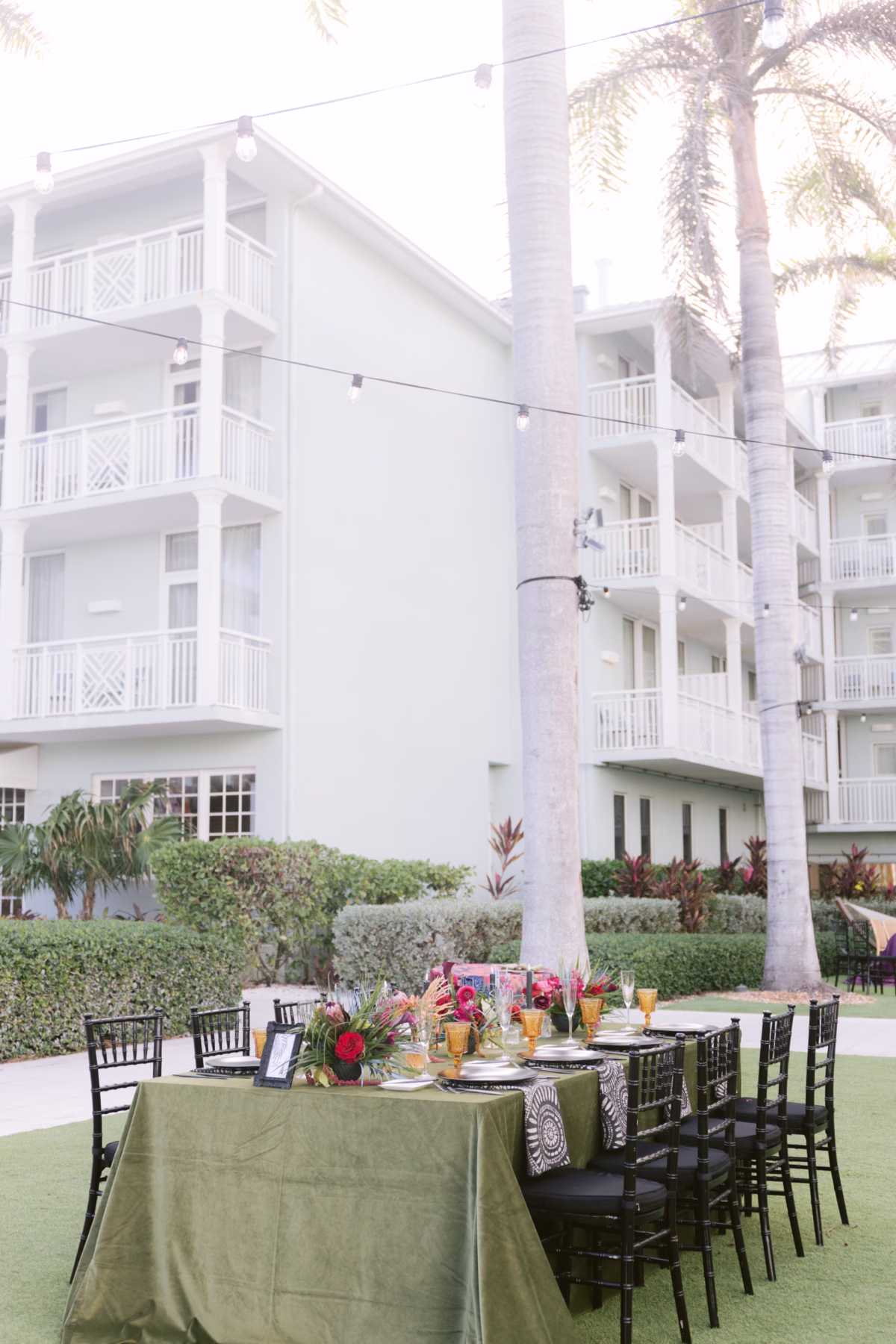 Elegant outdoor wedding reception table with green linens and tropical florals by Arms of Persephone at Casa Marina Key West resort