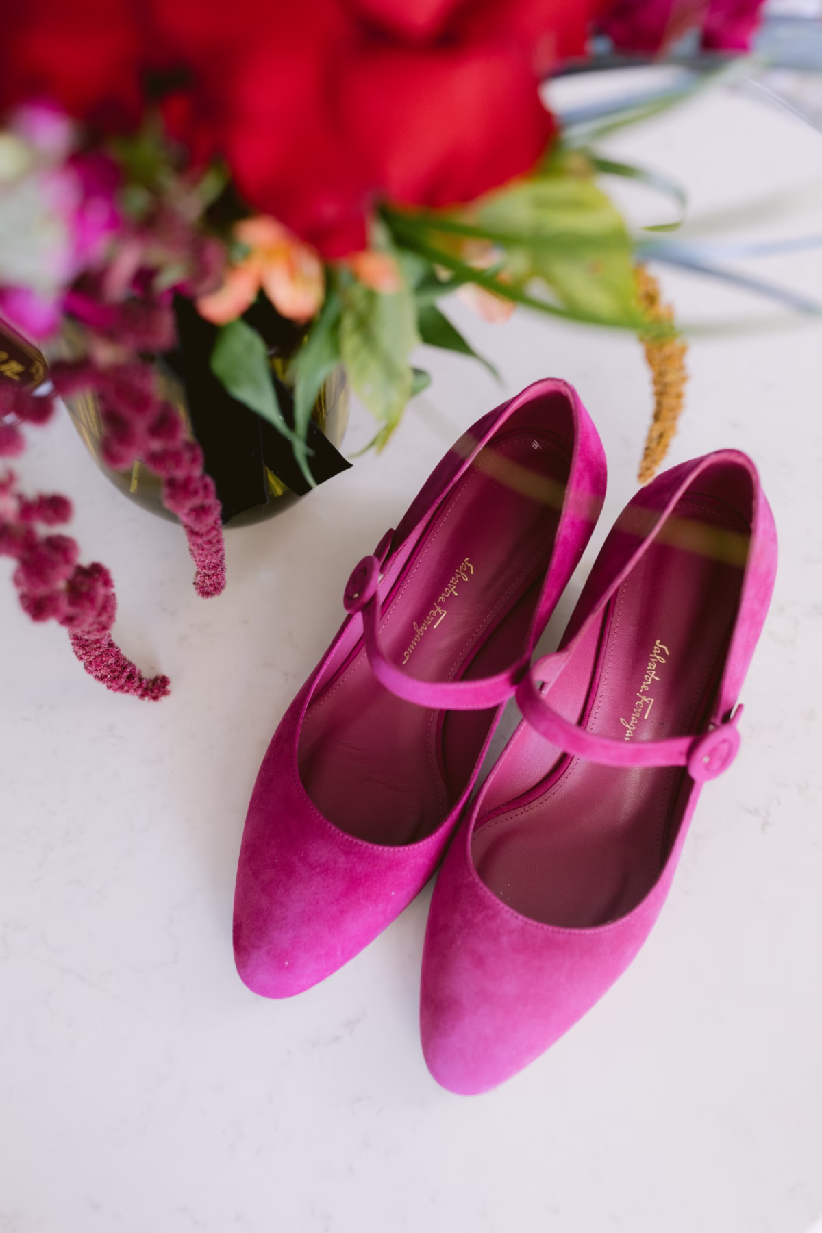 Bright pink wedding shoes displayed with colorful florals by Arms of Persephone at Casa Marina Key West captured by Tampa Bay wedding photographer Ashley Izquierdo Photography