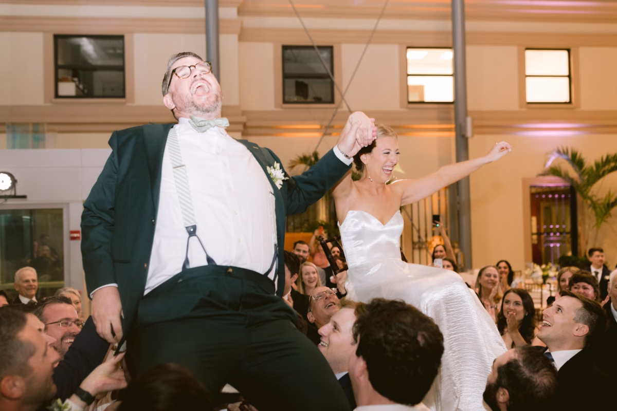 Bride and groom lifted on chairs during traditional Jewish hora dance at Nancy Cotto Events venue in St. Petersburg captured by Ashley Izquierdo Photography