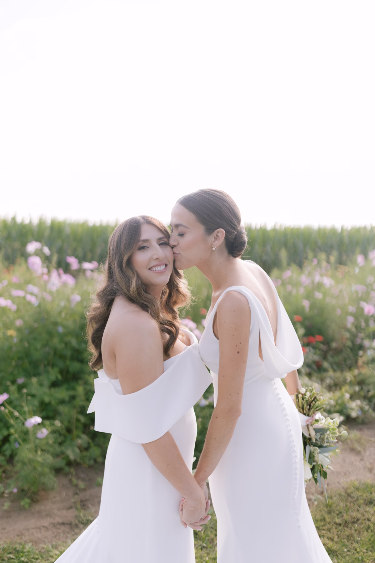 johnsons locust hall farm wedding kleinfeld dress allie johnson florals - A Farm Wedding at Johnson's Locust Hall, New Jersey Two brides in white dresses share an intimate moment among wildflowers at Johnson's Locust Hall farm wedding with Kleinfeld gowns and Allie Johnson florals