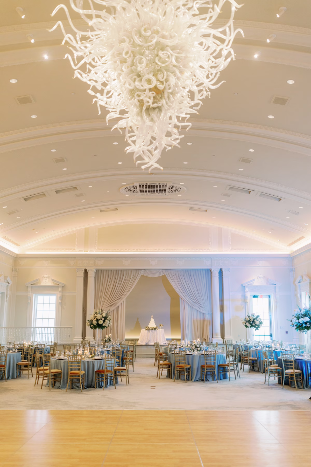 Elegant wedding reception ballroom with dramatic white chandelier and blue linens by Lemon Drops Weddings and Events at The Vinoy St. Petersburg
