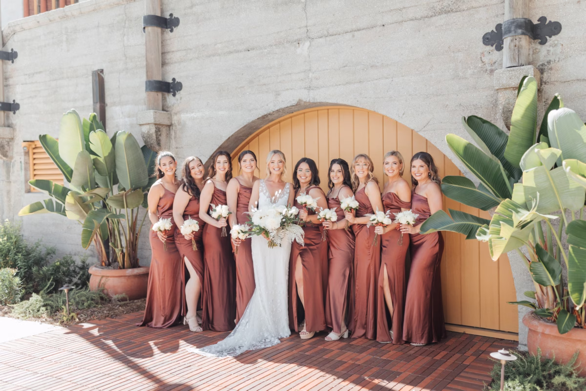 Bridal party in rust bridesmaid dresses with white bouquets by Aime Peterson Flowers at historic Lightner Museum wedding coordinated by Coastal Celebrations