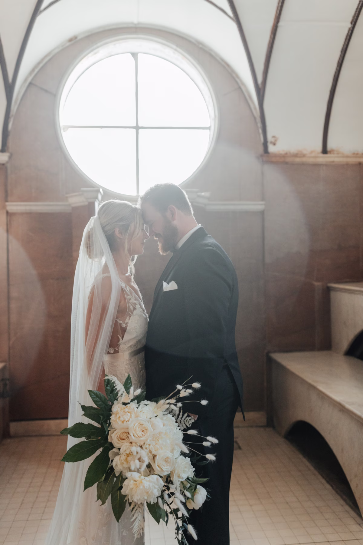 Bride and groom share intimate moment with white bouquet by Aime Peterson Flowers at historic Lightner Museum wedding in St. Augustine