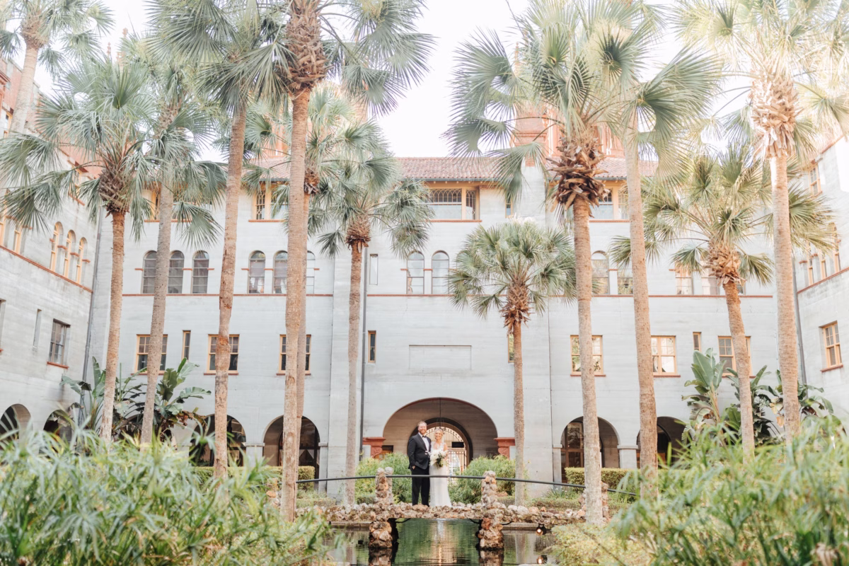 Historic wedding ceremony at The Lightner Museum courtyard with palm trees and Spanish colonial architecture, planned by Coastal Celebrations