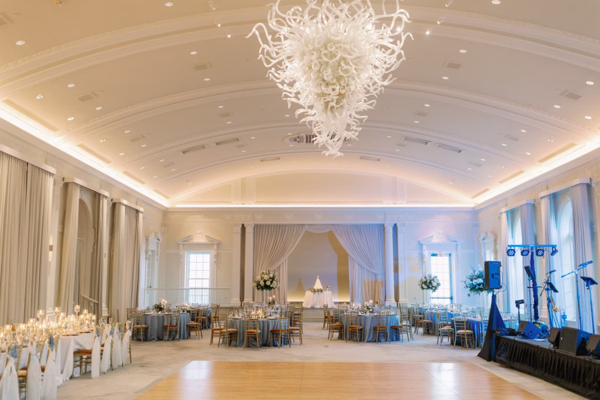 Elegant wedding reception ballroom at The Vinoy St. Petersburg with crystal chandelier, blue linens, and floral centerpieces by Lemon Drops Weddings and Events