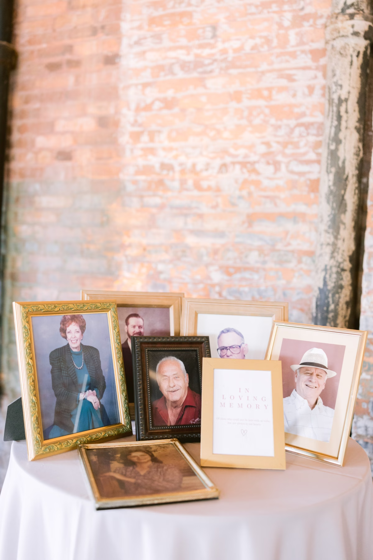 Framed memorial photos of deceased family members displayed on white table at Armature Works Tampa wedding planned by Seashine Weddings