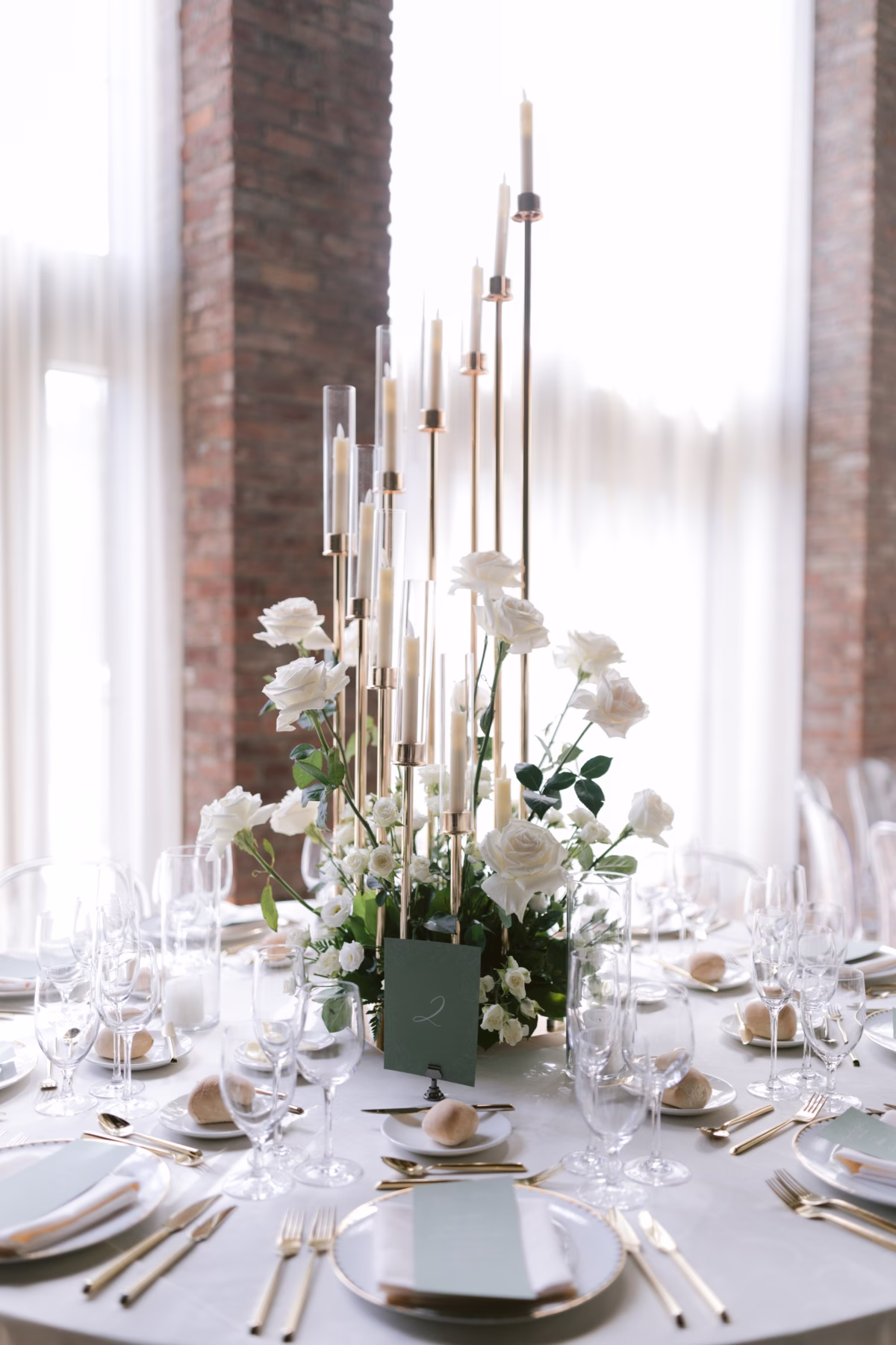 Elegant white wedding tablescape with tall candlesticks and white roses by Maky The Diva Flowers at The Roundhouse Beacon Hudson Valley venue