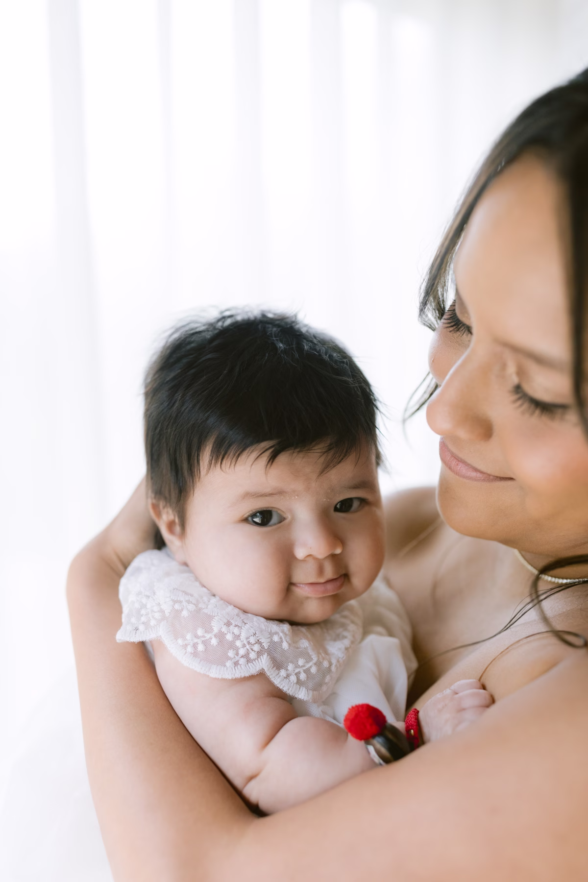 Mother holding baby in white lace dress at The Roundhouse Beacon wedding photographed by Ashley Izquierdo Photography