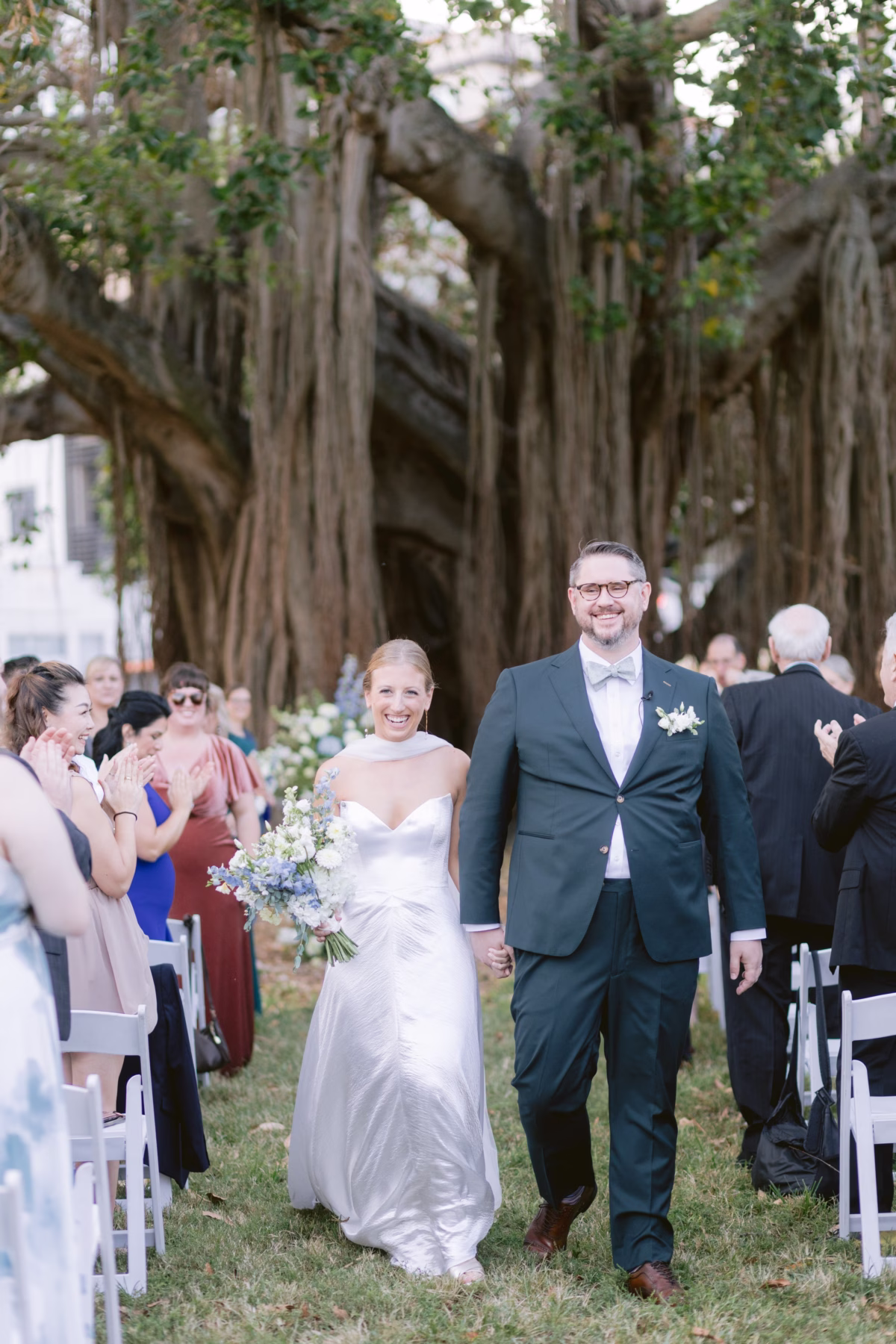 Bride and groom walking down aisle after outdoor wedding ceremony with white florals by Wonderland Floral Art at Nancy Cotto Events venue in St. Petersburg