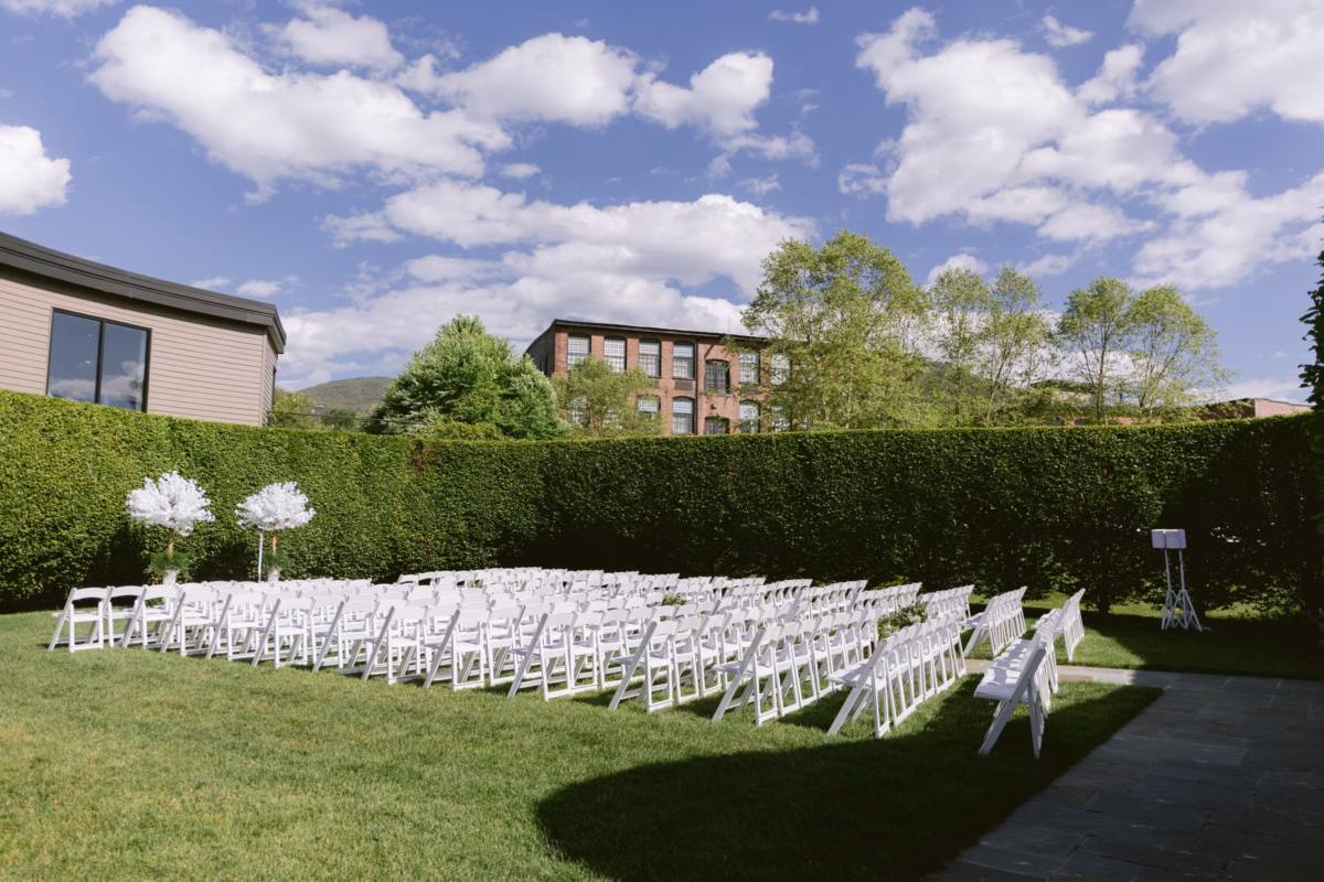Outdoor wedding ceremony setup with white chairs and floral arrangements at The Roundhouse Beacon venue by Maky The Diva Flowers in Hudson Valley