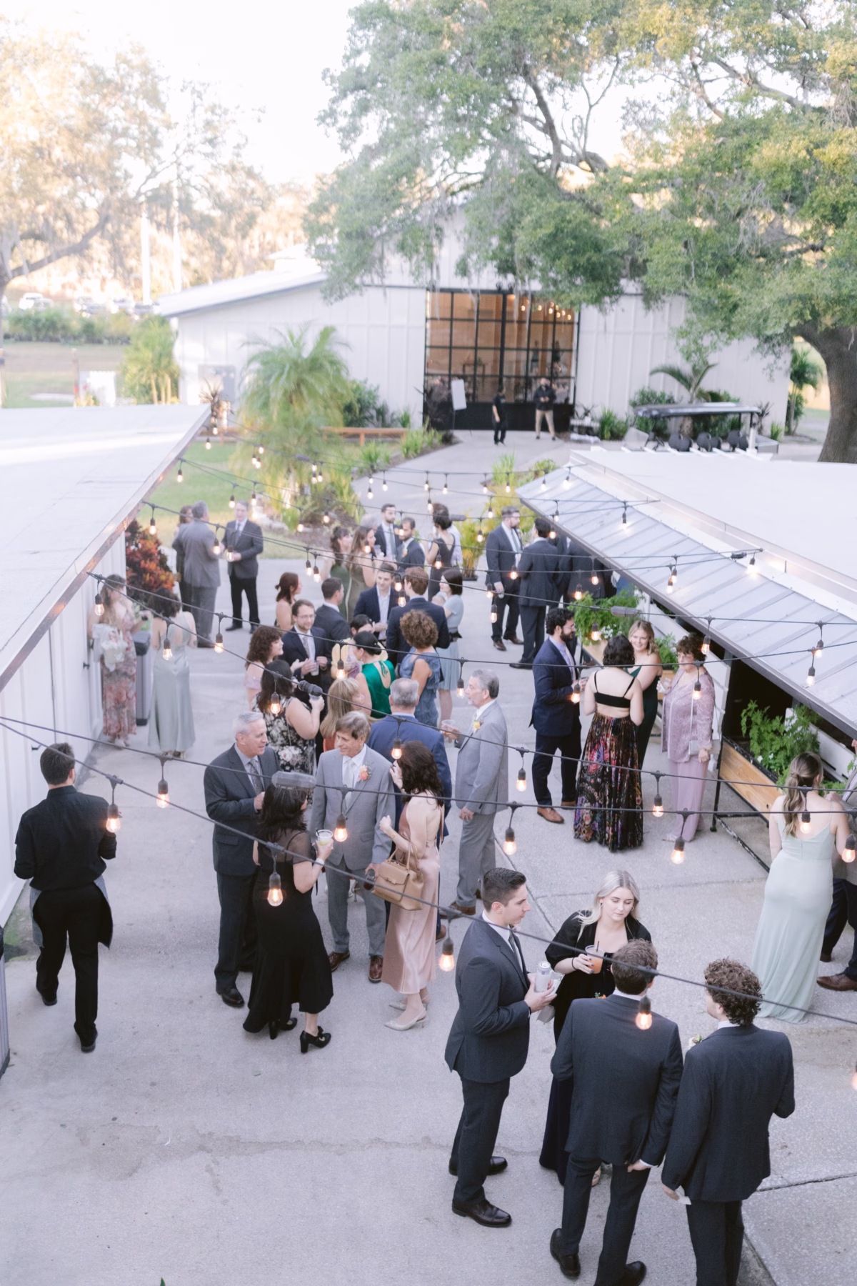 Elegant outdoor wedding cocktail hour with string lights and guests mingling at Soire Estate Tampa venue photographed by Ashley Izquierdo Photography