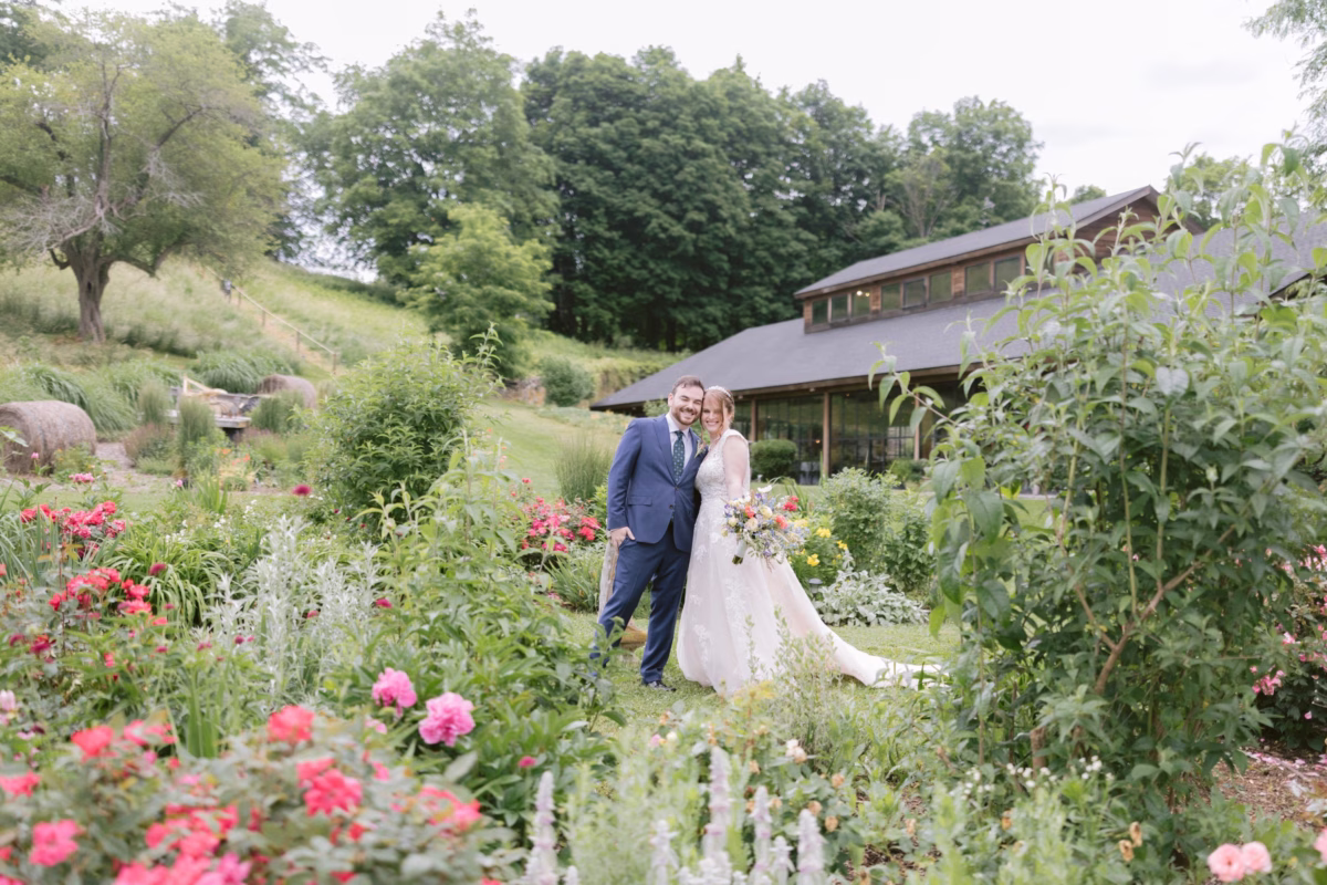 Bride and groom pose among vibrant wildflowers and lush gardens at Red Maple Vineyard wedding with floral design by Cherry Brandy Designs
