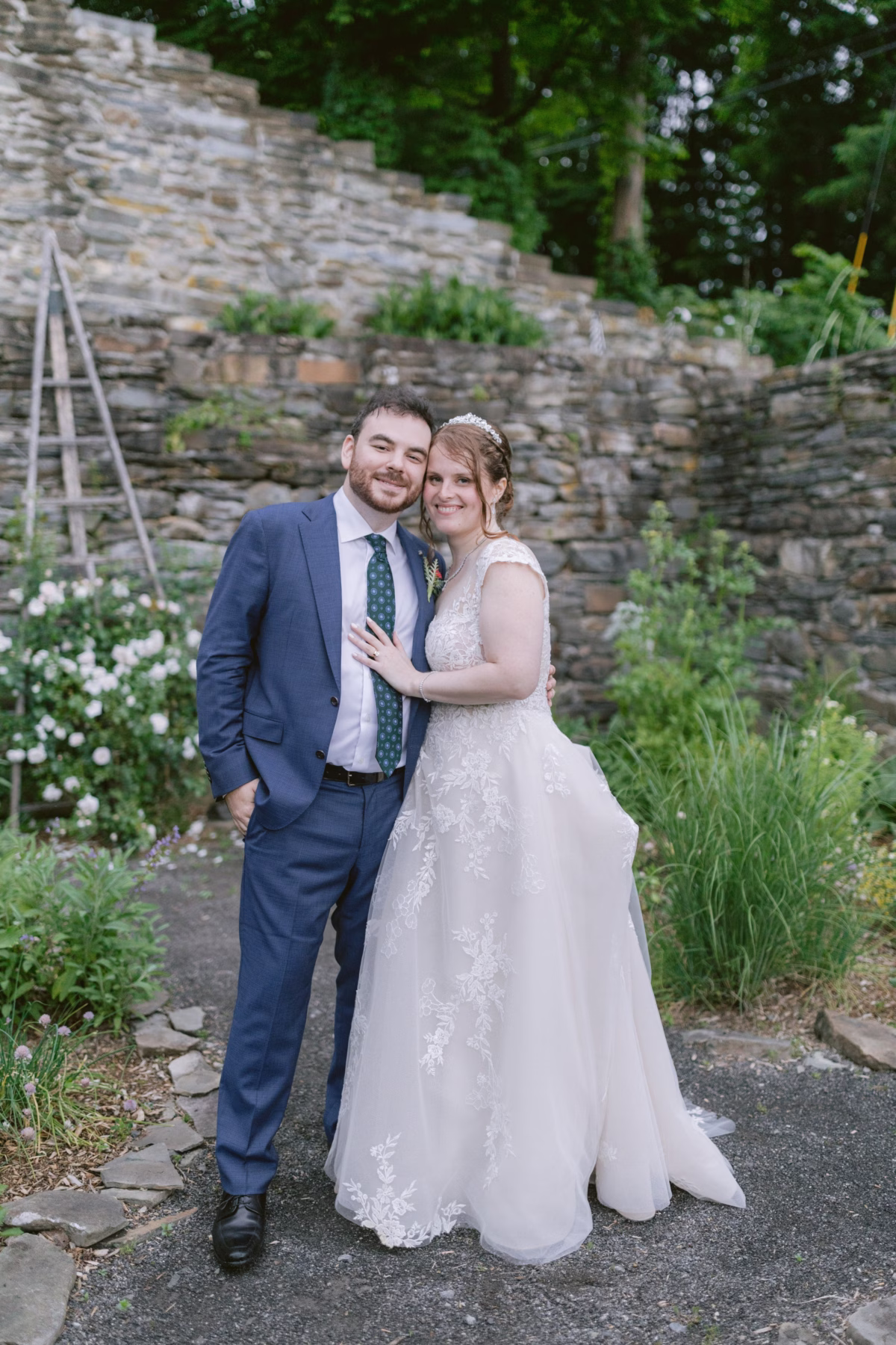 Bride and groom embrace for romantic wedding portrait among stone ruins and gardens at Red Maple Vineyard, captured by Ashley Izquierdo Photography