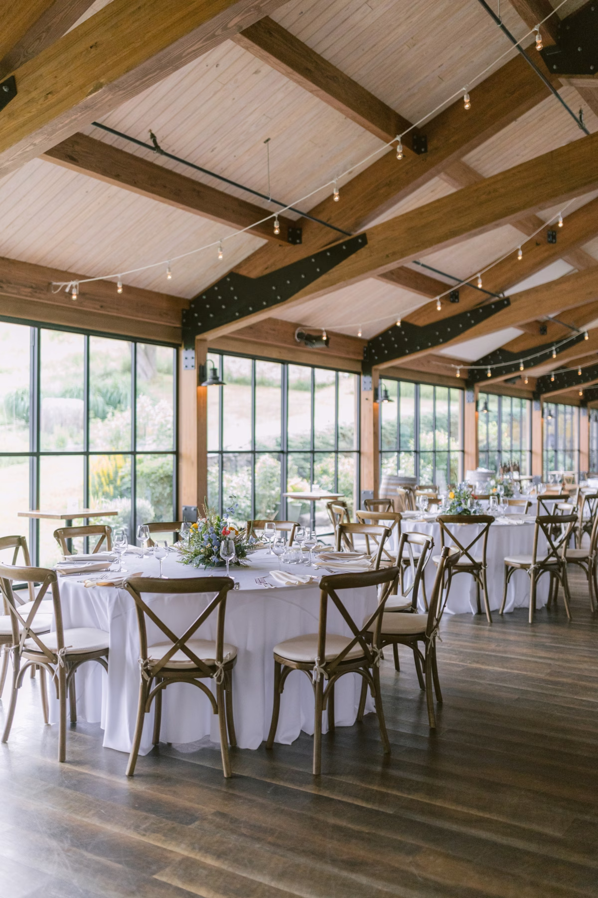 Wedding reception setup with cross-back chairs and wildflower centerpieces by Cherry Brandy Designs at Red Maple Vineyard in Tampa Bay