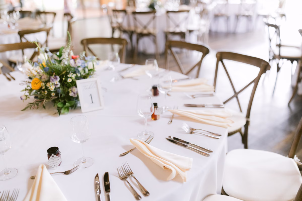 Elegant wedding reception table setting with wildflower centerpieces by Cherry Brandy Designs at Red Maple Vineyard featuring cross-back chairs and white linens