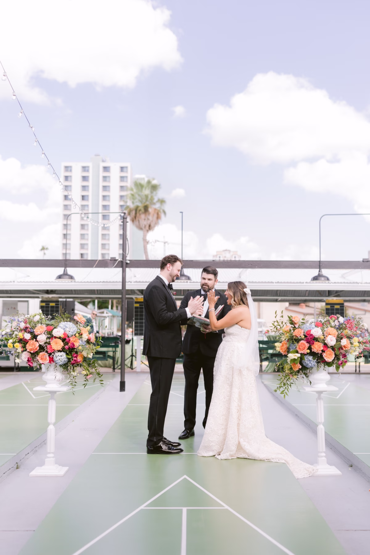 Rooftop wedding ceremony with colorful floral arrangements by Petite Fleur at St. Pete Shuffleboard Club captured by Tampa Bay wedding photographer Ashley Izquierdo Photography