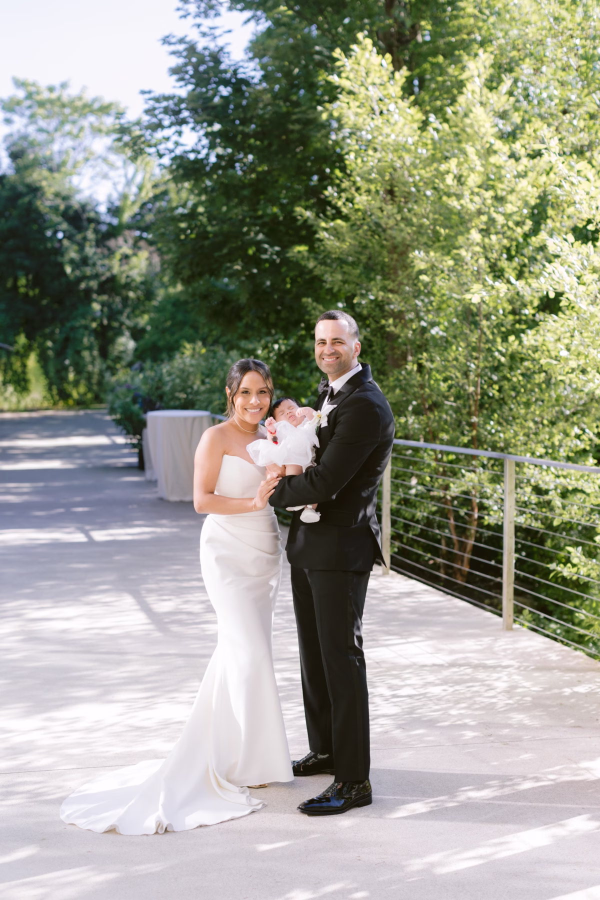 Bride and groom holding newborn baby in elegant wedding attire at The Roundhouse Beacon Hudson Valley venue photographed by Ashley Izquierdo Photography