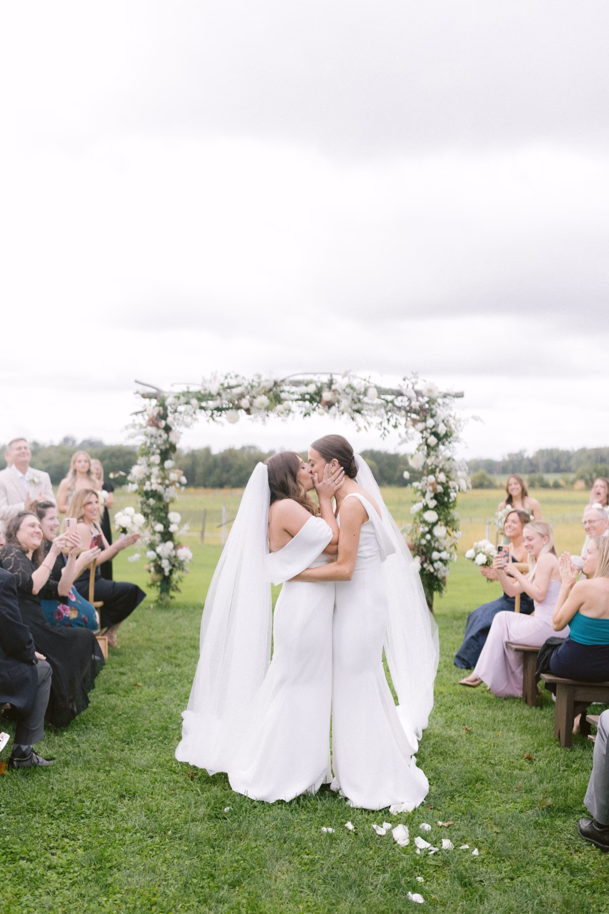 same sex wedding ceremony kiss johnsons locust hall florist allie johnson - A Farm Wedding at Johnson's Locust Hall, New Jersey Two brides sharing their first kiss under a lush floral arch by Allie Johnson at their farm wedding ceremony at Johnson's Locust Hall in New Jersey