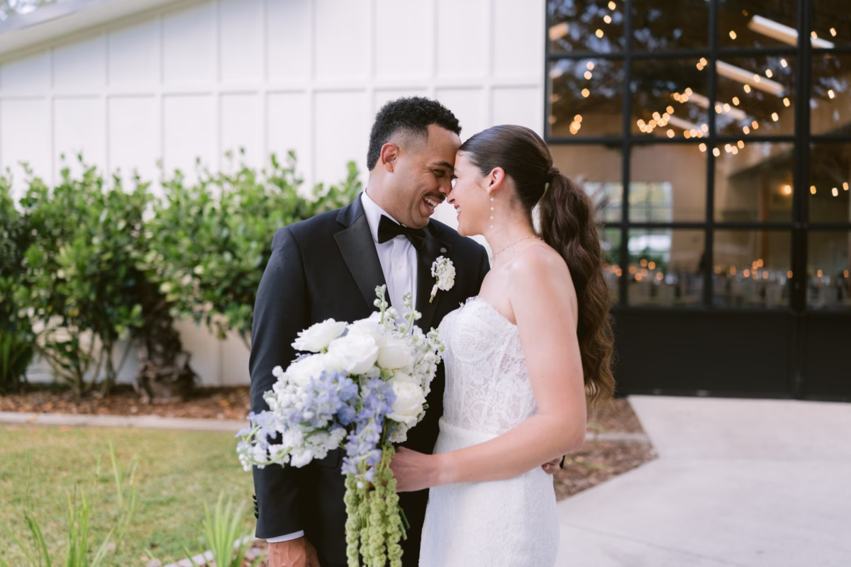 Bride and groom sharing intimate moment with white and blue wedding bouquet by Ava Elise Decor at Soire Estate Tampa wedding photographed by Ashley Izquierdo Photography