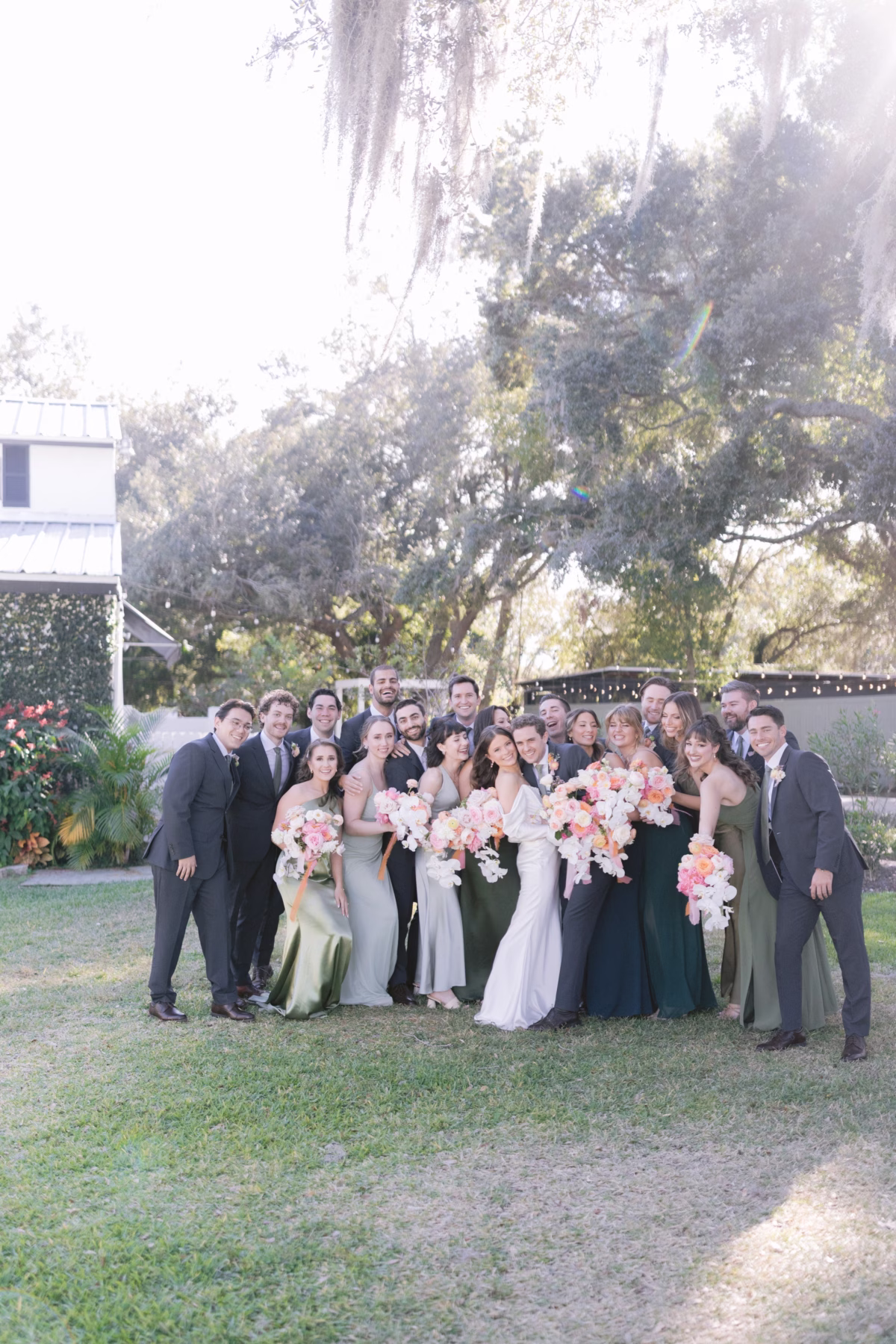 Wedding party group photo with coral and pink bridal bouquets by Golden Wild Florals at Soire Estate Tampa garden wedding