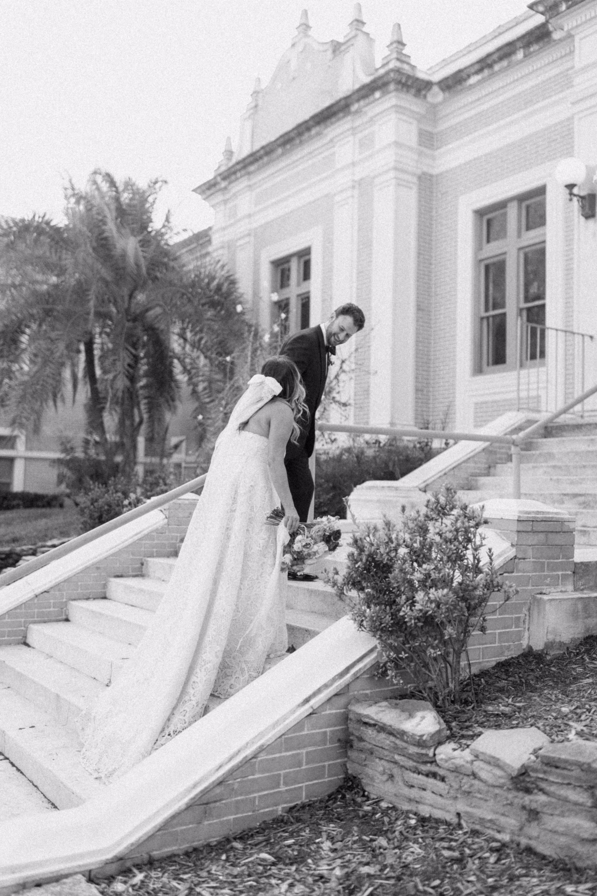 Bride in BHLDN wedding dress and groom sharing intimate moment on steps at St Pete Shuffleboard Club wedding coordinated by Day of Details