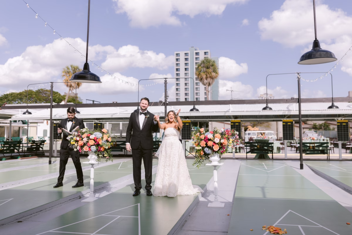 Bride and groom celebrate their wedding ceremony on shuffleboard courts at St. Pete Shuffleboard Club with colorful floral arrangements by Petite Fleur and coordination by Day of Details