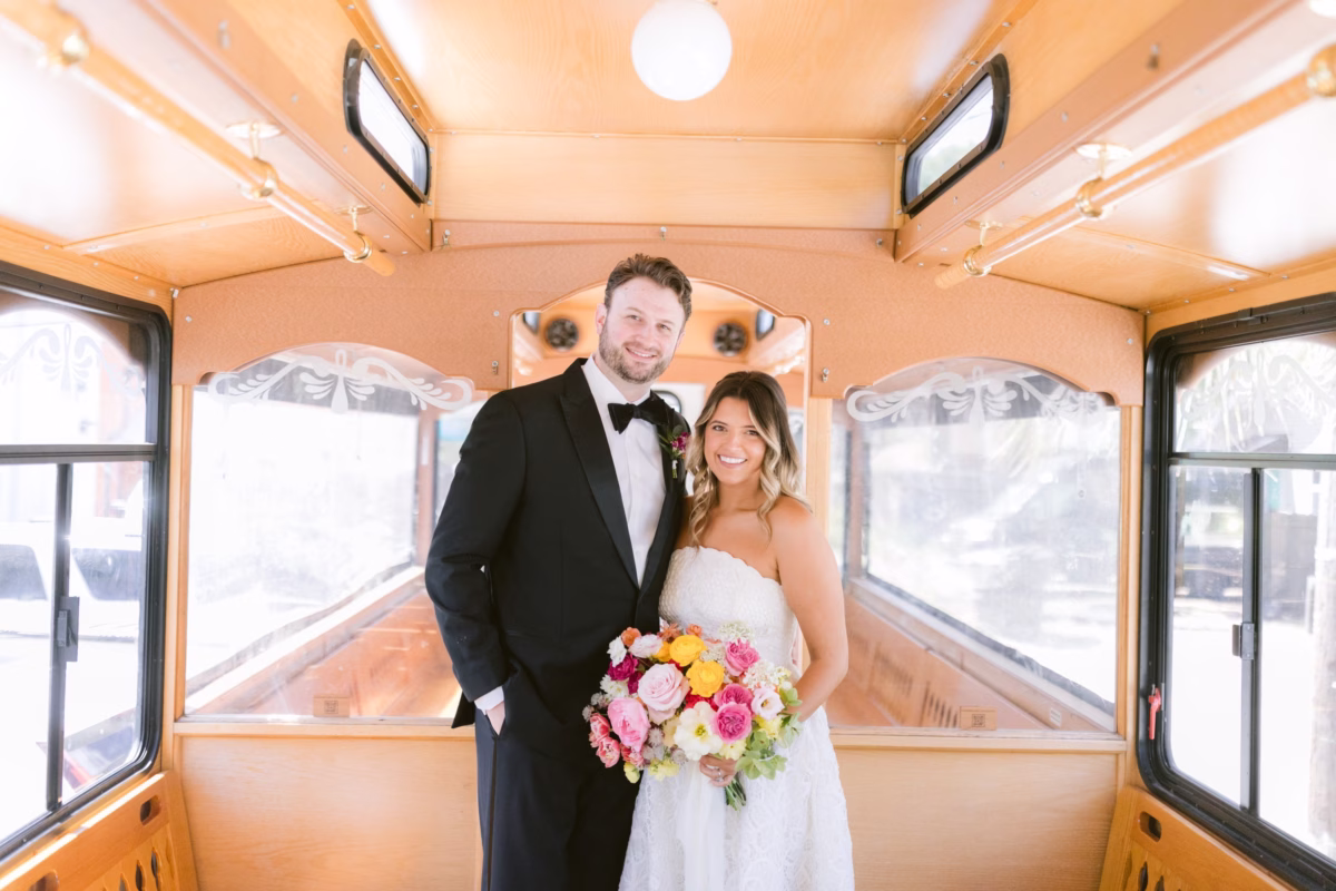 Bride and groom pose inside vintage trolley with colorful Petite Fleur bouquet at St Pete Shuffleboard Club wedding in Tampa Bay
