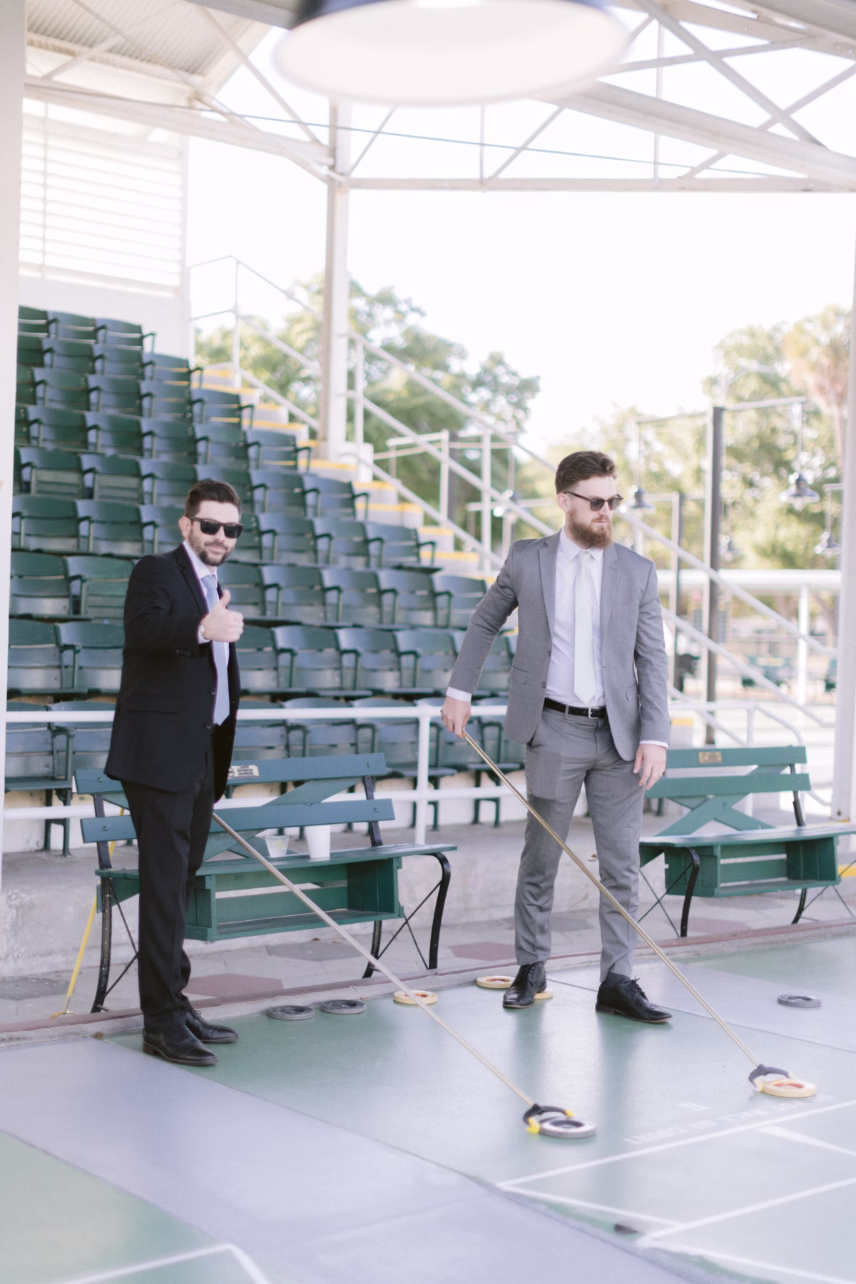 Groom and groomsman in suits playing shuffleboard at St. Pete Shuffleboard Club wedding venue in Tampa Bay