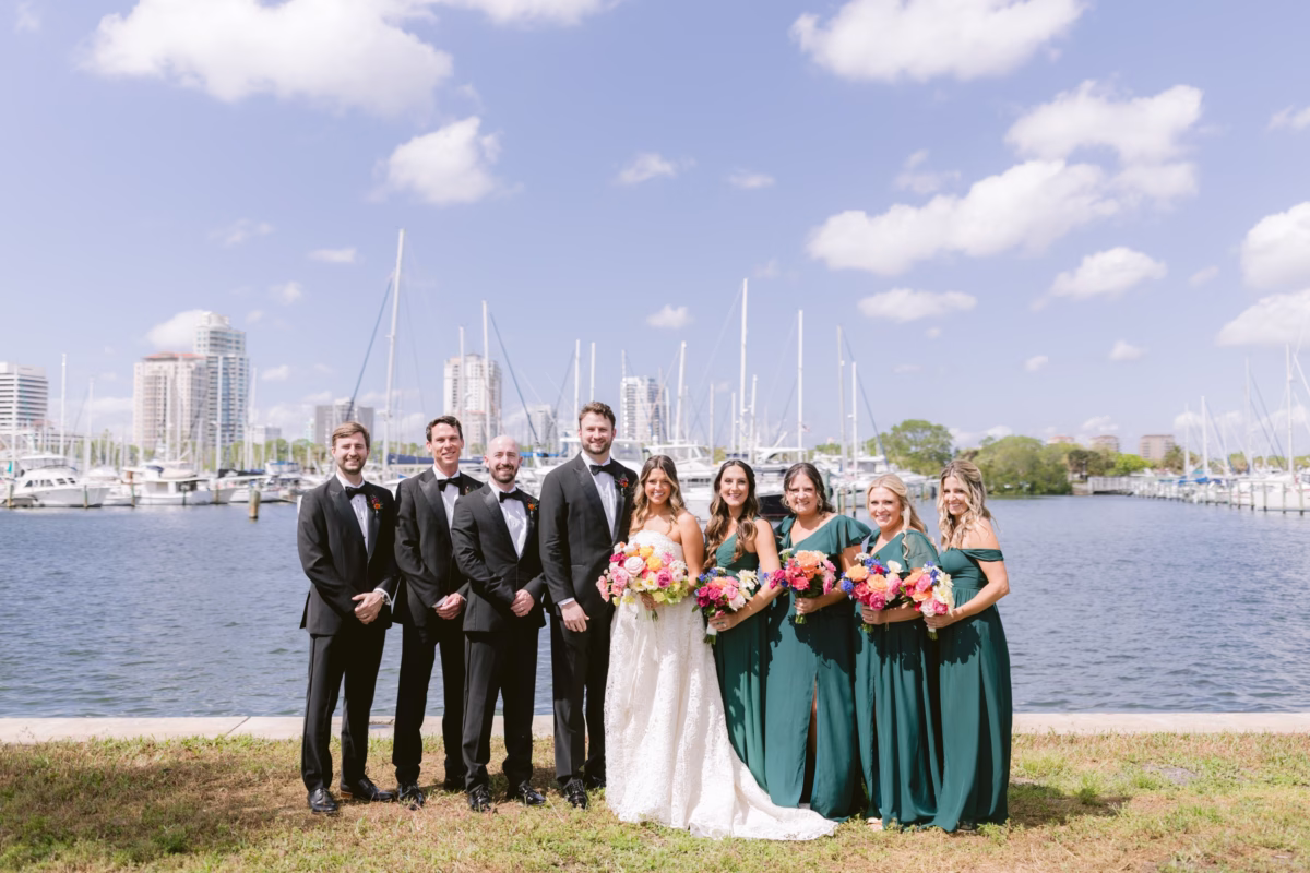 Wedding party portrait with emerald bridesmaids and vibrant bouquets by Petite Fleur at St. Pete Shuffleboard Club marina coordinated by Day of Details