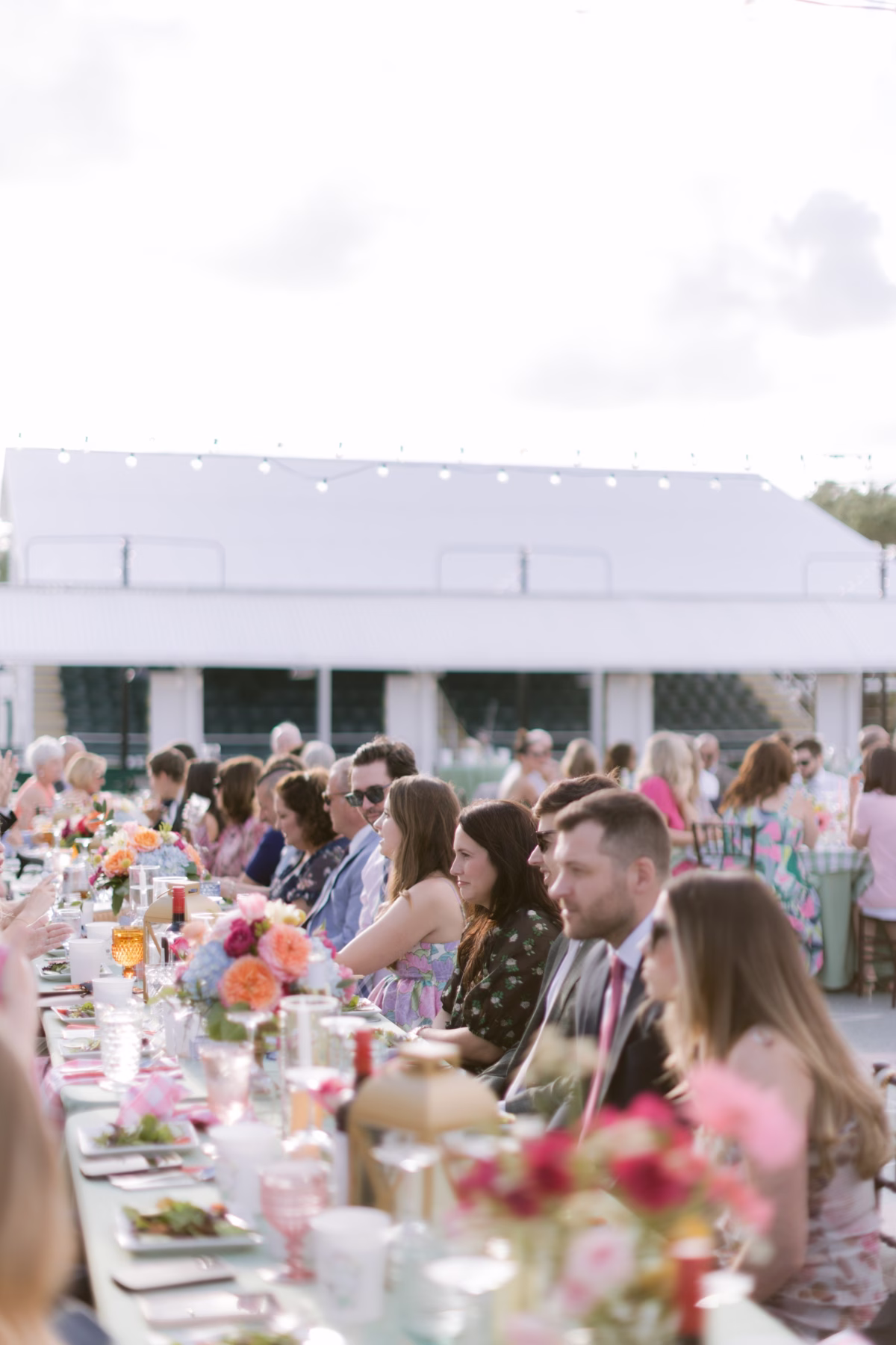 Colorful outdoor wedding reception at St Pete Shuffleboard Club with vibrant floral centerpieces by Petite Fleur and guests dining at long tables