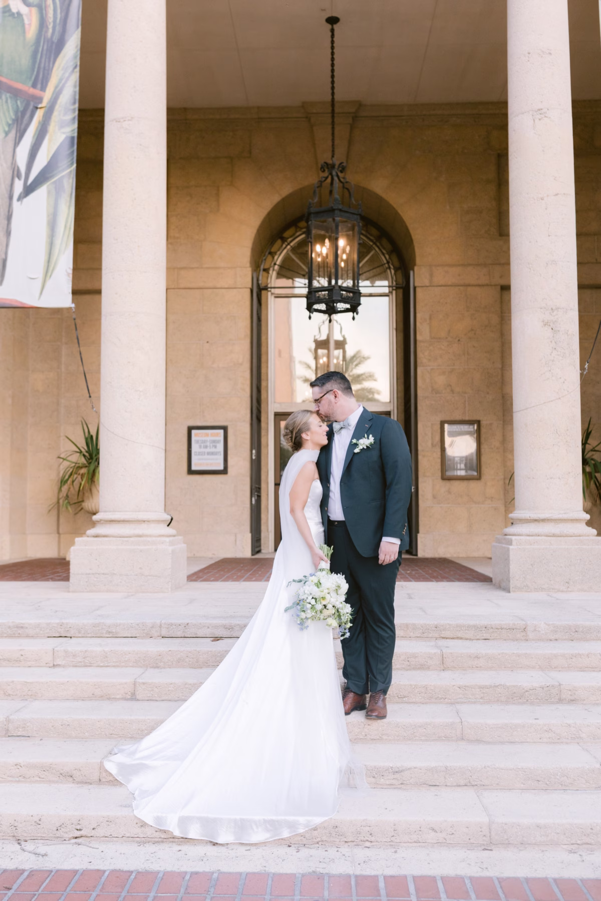 Elegant wedding portrait at St. Petersburg art museum featuring bride and groom with white bouquet by Wonderland Floral Art