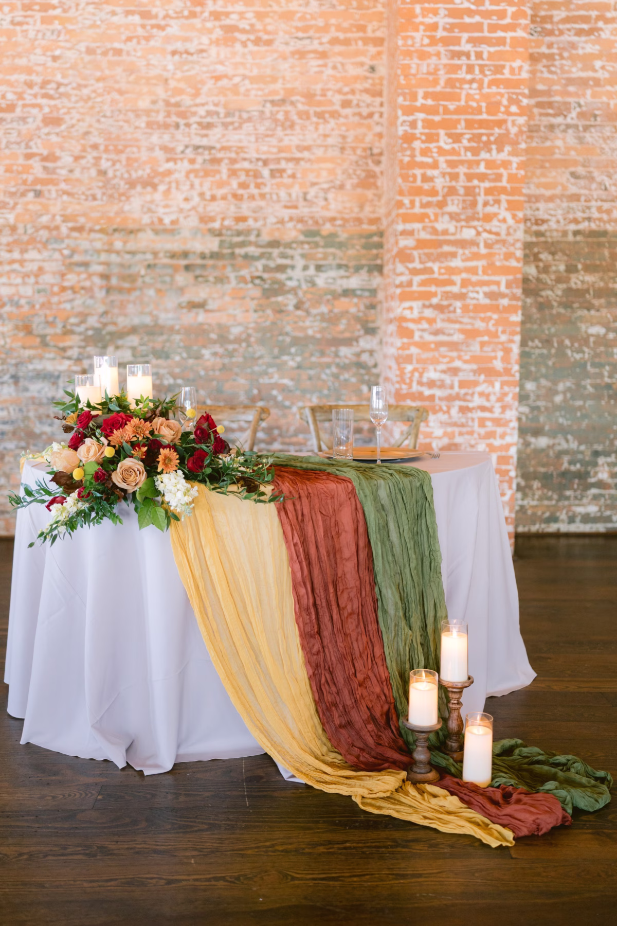 Elegant sweetheart table with fall floral centerpiece by Events in Bloom and colorful fabric draping at Armature Works Tampa wedding