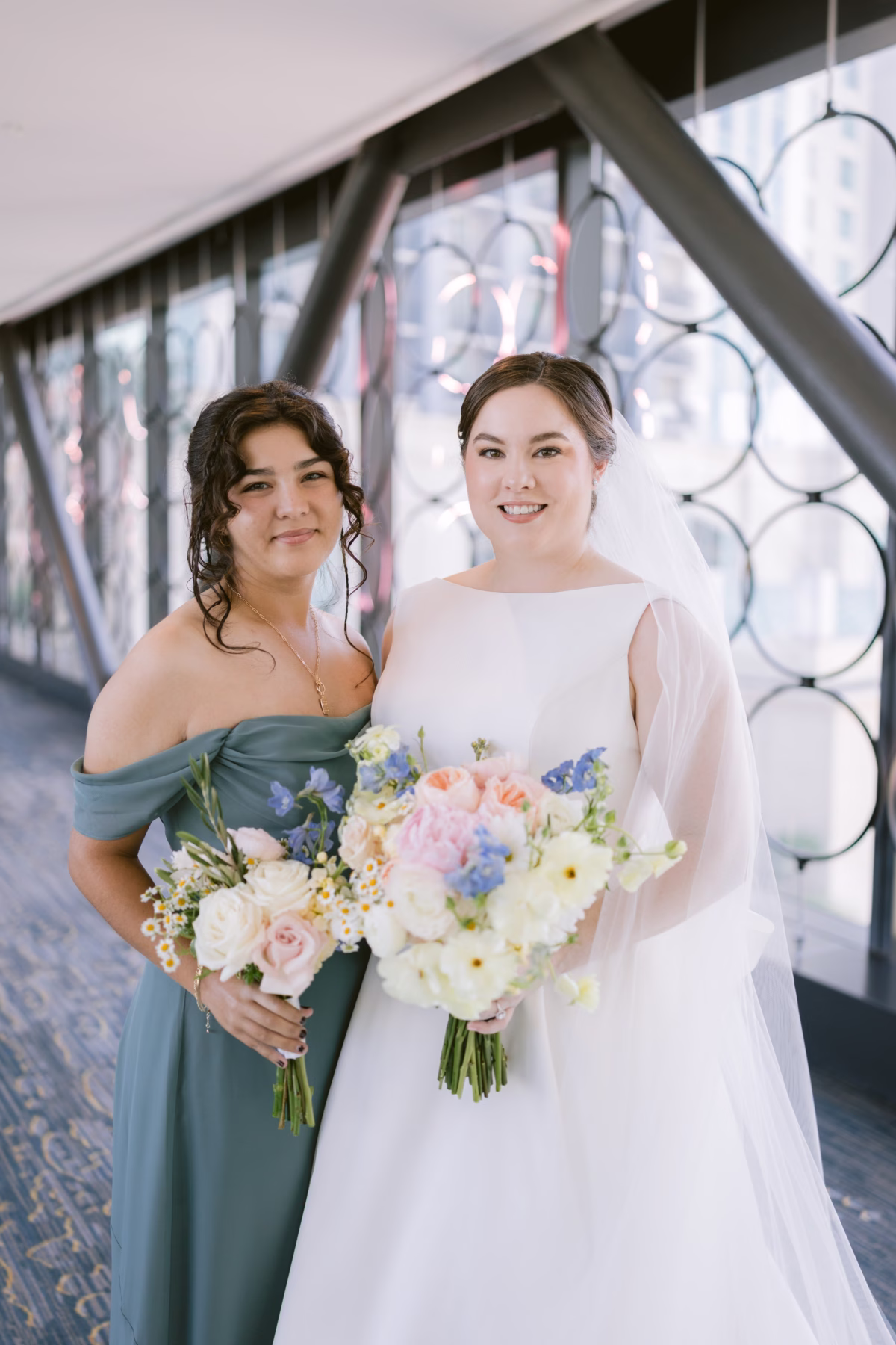 Bride and bridesmaid holding wedding bouquets by I Dew Events florist at Armature Works Tampa wedding photographed by Ashley Izquierdo Photography