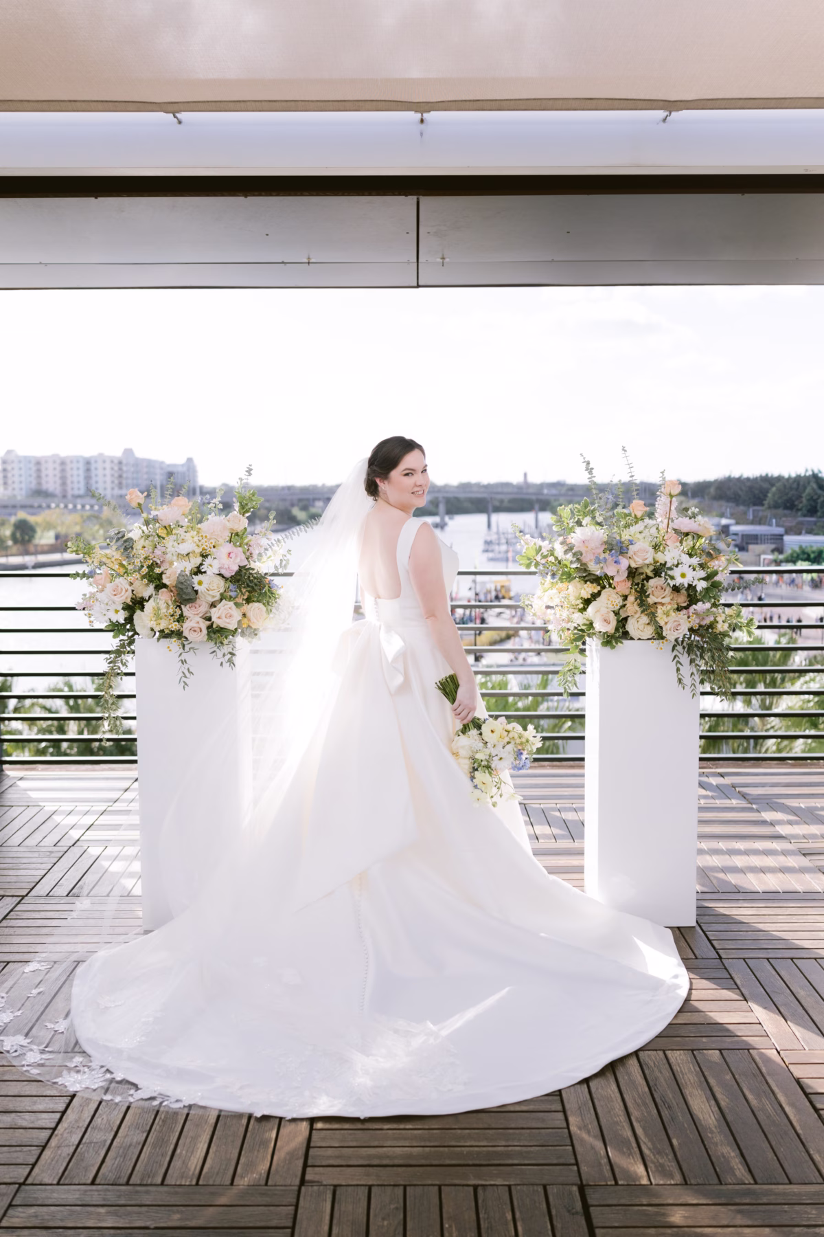 Bride in flowing wedding gown from The White Closet Bridal poses with bouquet by I Dew Events florist at Armature Works rooftop ceremony in Tampa