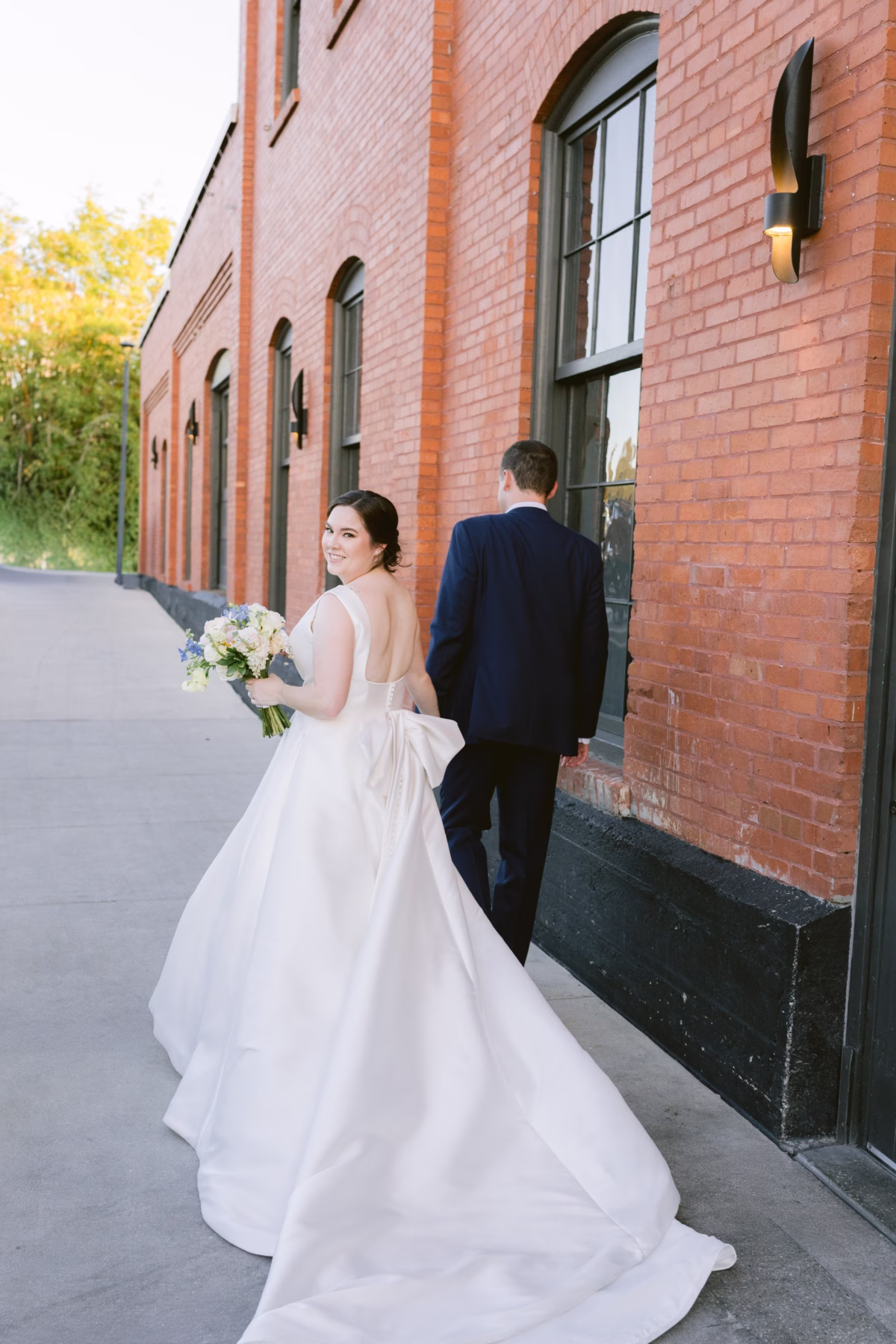 Bride in White Closet Bridal gown holding I Dew Events bouquet with groom at Armature Works Tampa wedding photographed by Ashley Izquierdo Photography