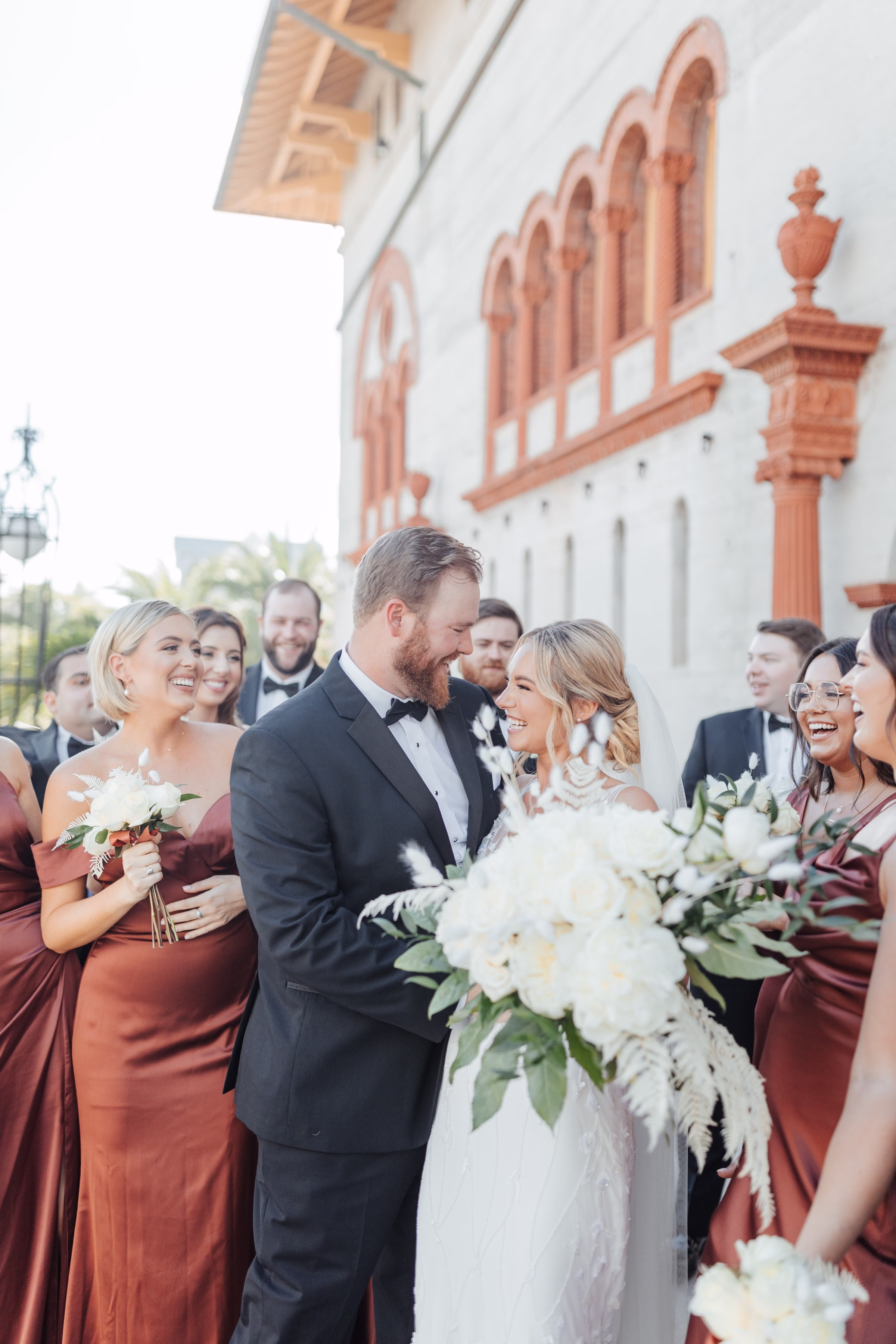 tampa bay wedding photographer bridal party historic venue - Home Bride and groom sharing an intimate moment surrounded by their wedding party in burgundy dresses at a historic Tampa Bay venue captured by Ashley Izquierdo Photography